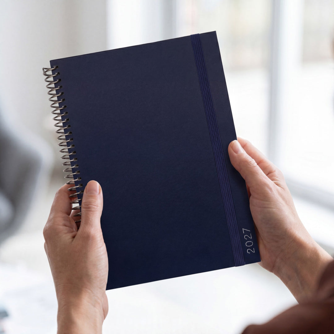 2027 Midnight Weekly Slimline Teacher Planner styled on a desk with glasses, keys and a coffee