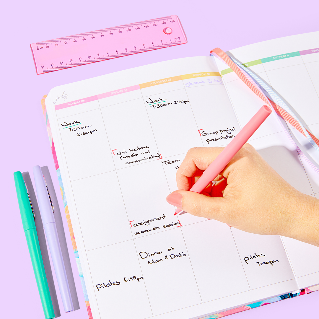 Person writing in a teacher planner with a supplied pen, showcasing the planner's organised layout and the smooth functionality of the pen.
