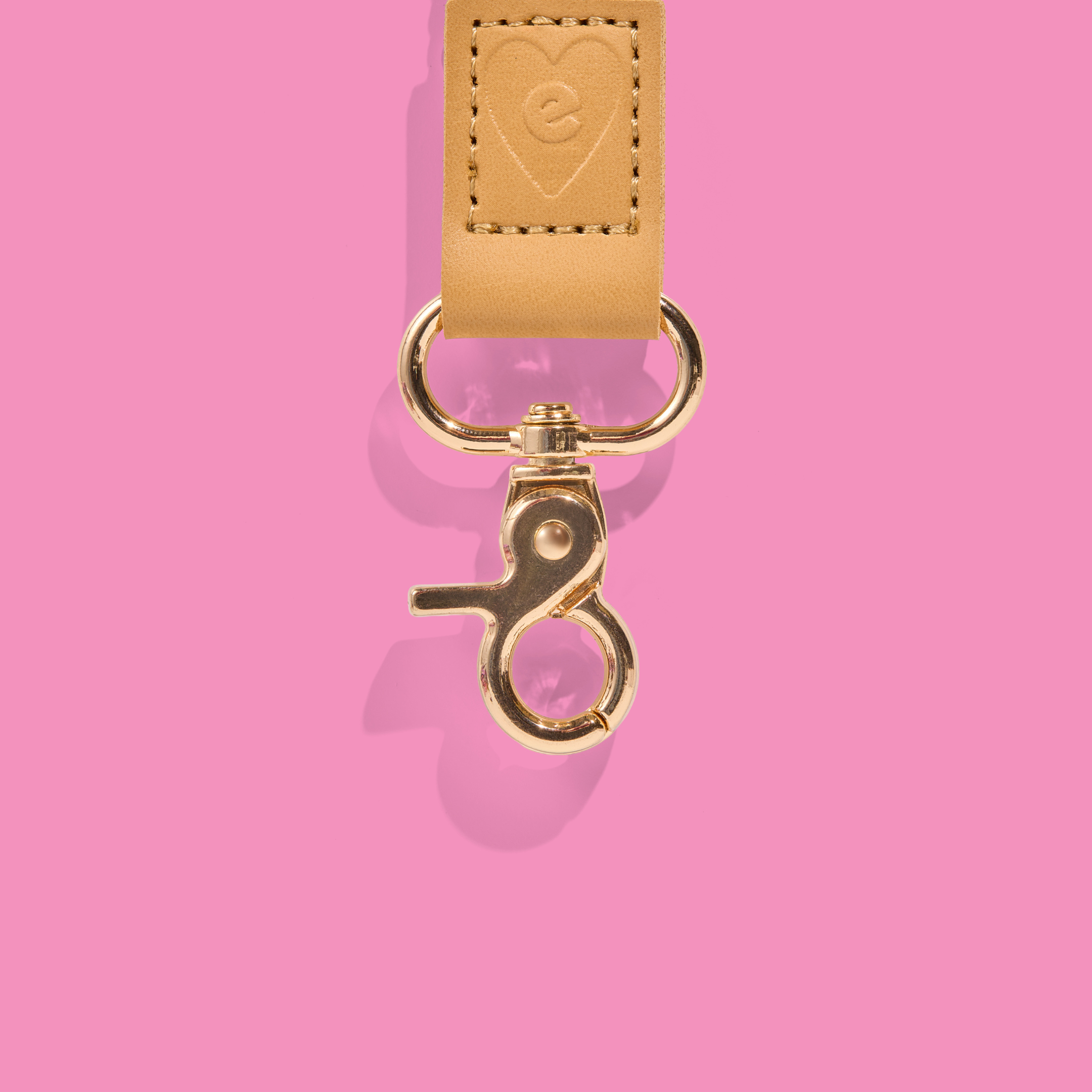 Gold clasp and tan leather detail of a teacher lanyard embossed with the Mrs Edgar logo, set against a pink background.
