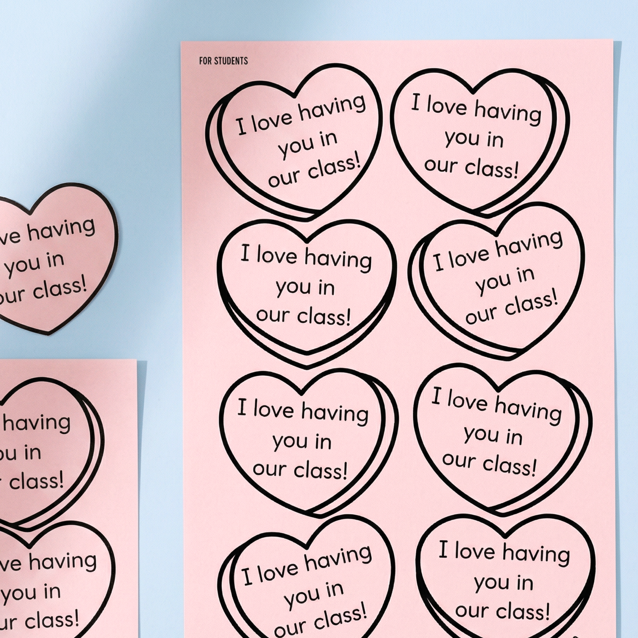 Two printable lunchbox note sheets on pink paper with heart designs and positive messages, styled on a pastel blue background.