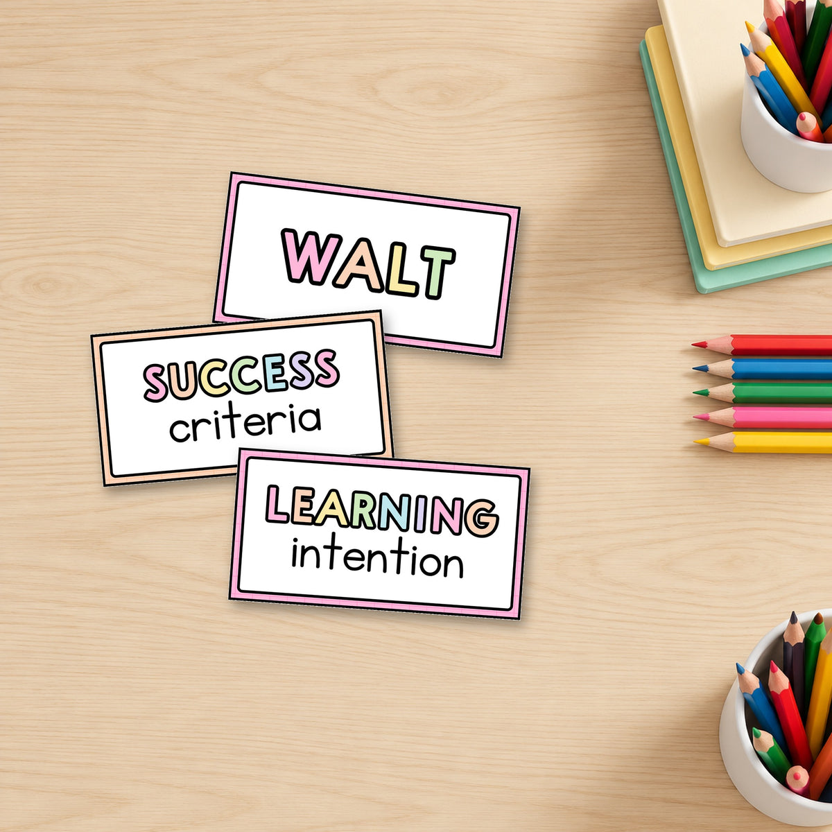 Three rainbow-caps Learning Intention and Success Criteria signs standing on a teacher's desk