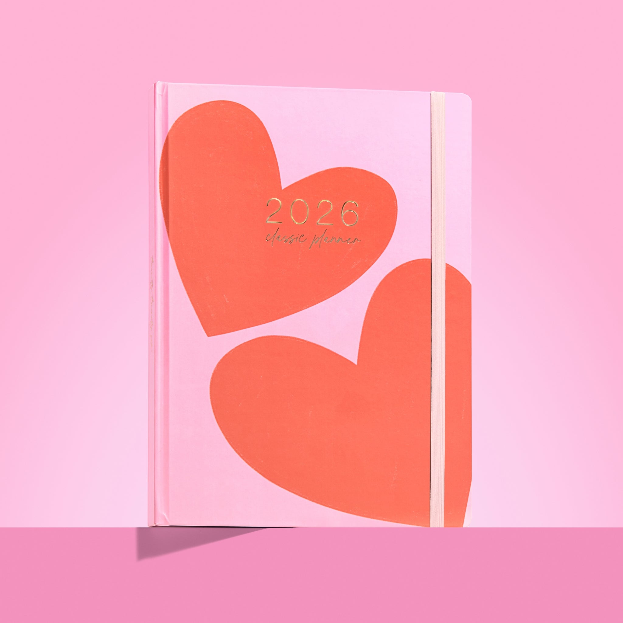 Pink planner with orange hearts and '2026' text on a pink background