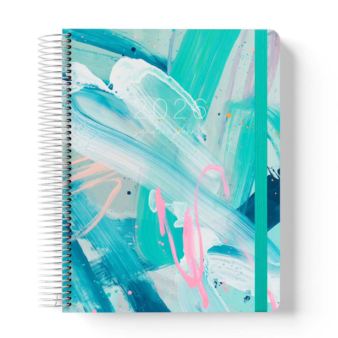 2026 teacher planner with abstract tropical brushstroke cover in teal, pink, and white, silver coil binding, and teal elastic strap.