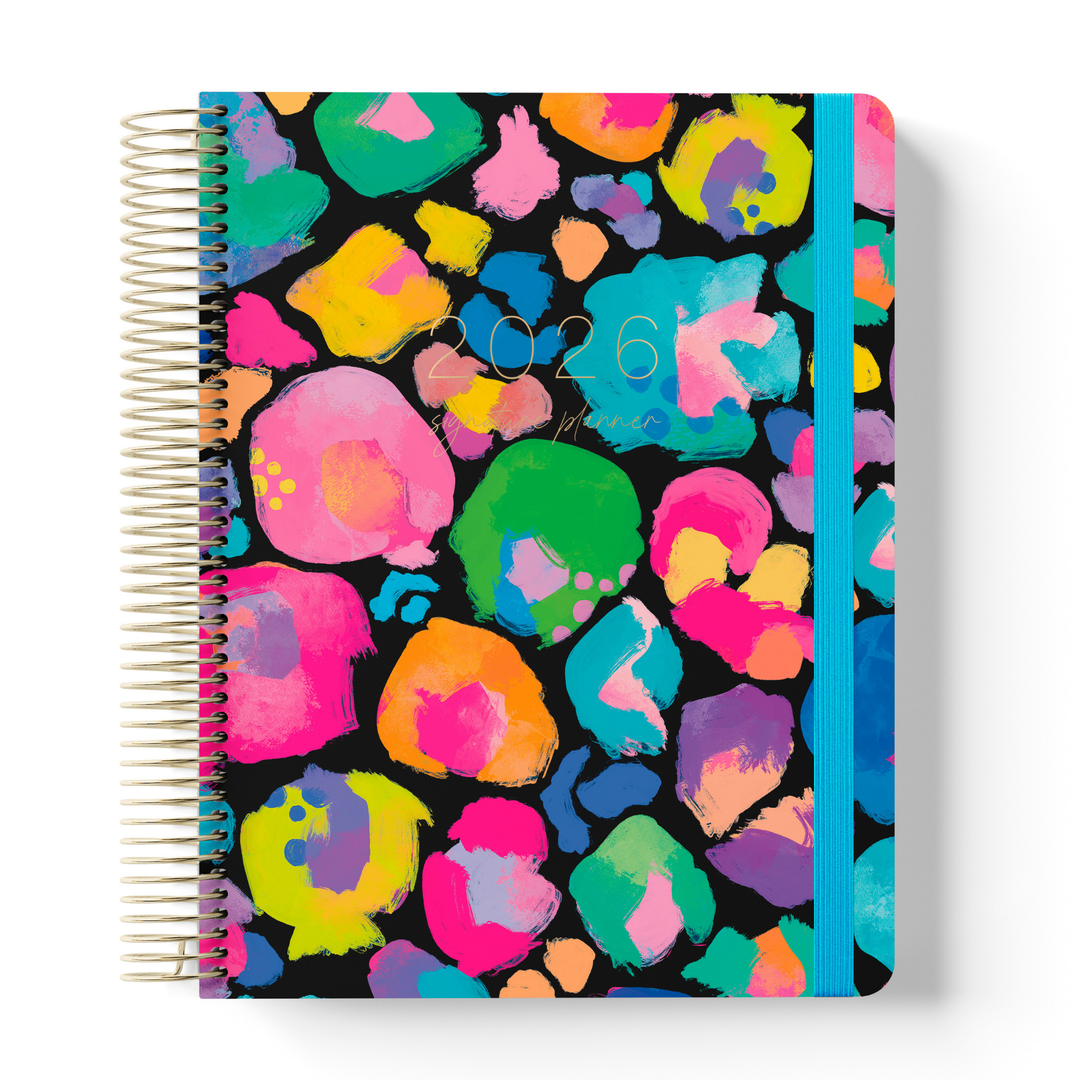 2026 signature planner with vibrant, multicoloured abstract leopard spots on a black cover, spiral-bound with a bright blue strap.