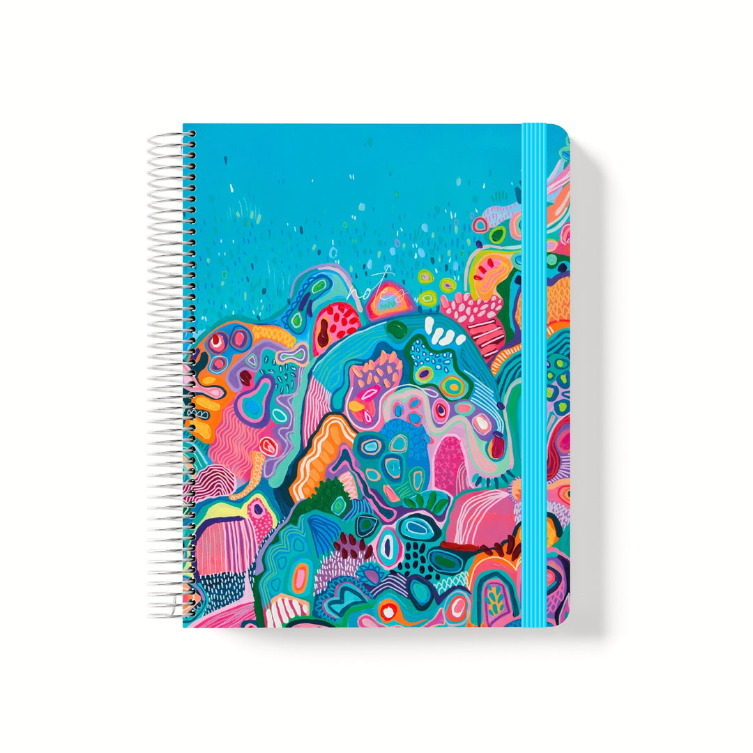 Coiled notebook with bright underwater reef artwork, featuring bold abstract shapes and a blue elastic band on a turquoise background.