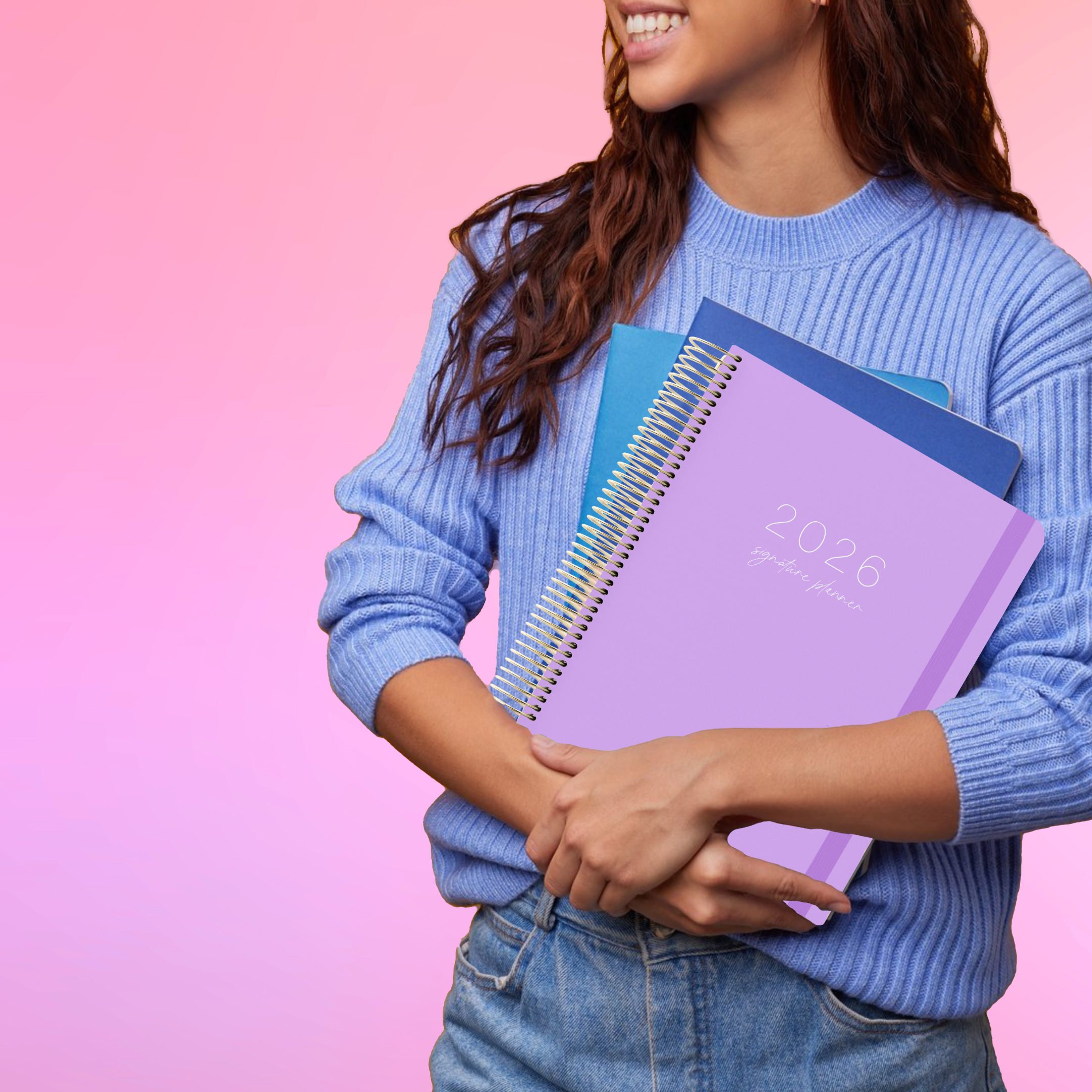 Person holding a spiral-bound lilac planner with a pink and purple gradient background
