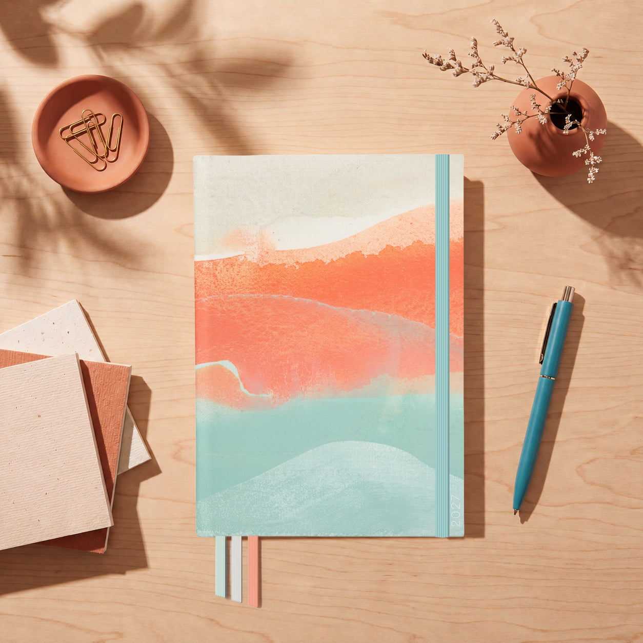 2027 Dreamy Afternoon Slimline Classic Teacher Planner flat lay with coral and seafoam watercolour cover, styled with a teal pen on a timber desk