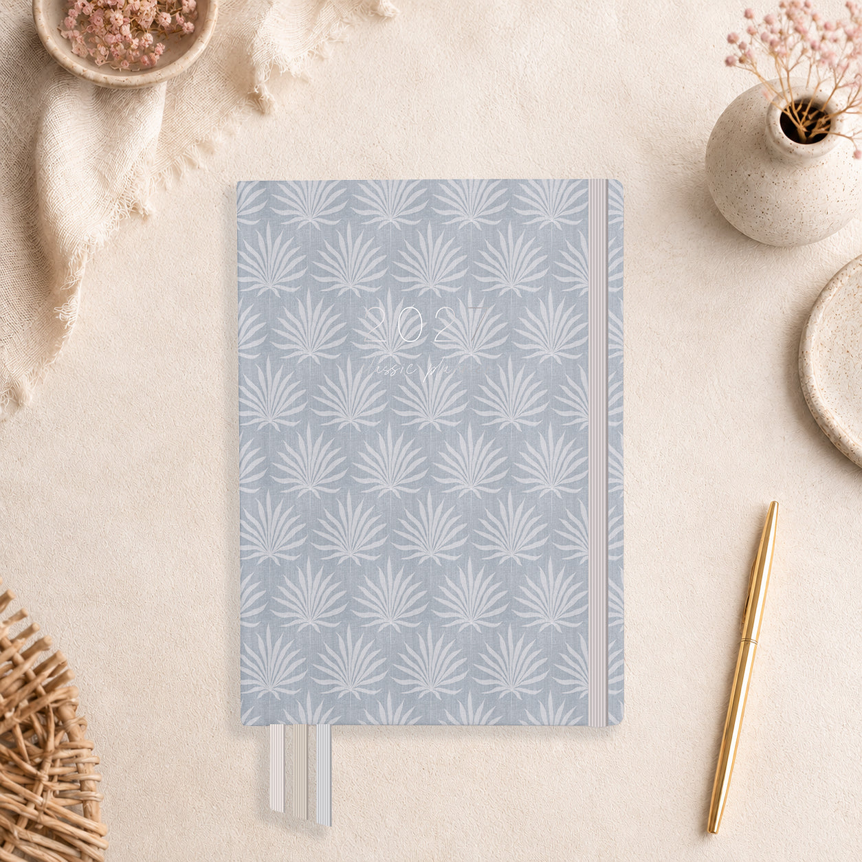 2027 Palms Classic Weekly Teacher Planner flat lay with blue-grey palm fan cover, styled with dried florals and a gold pen