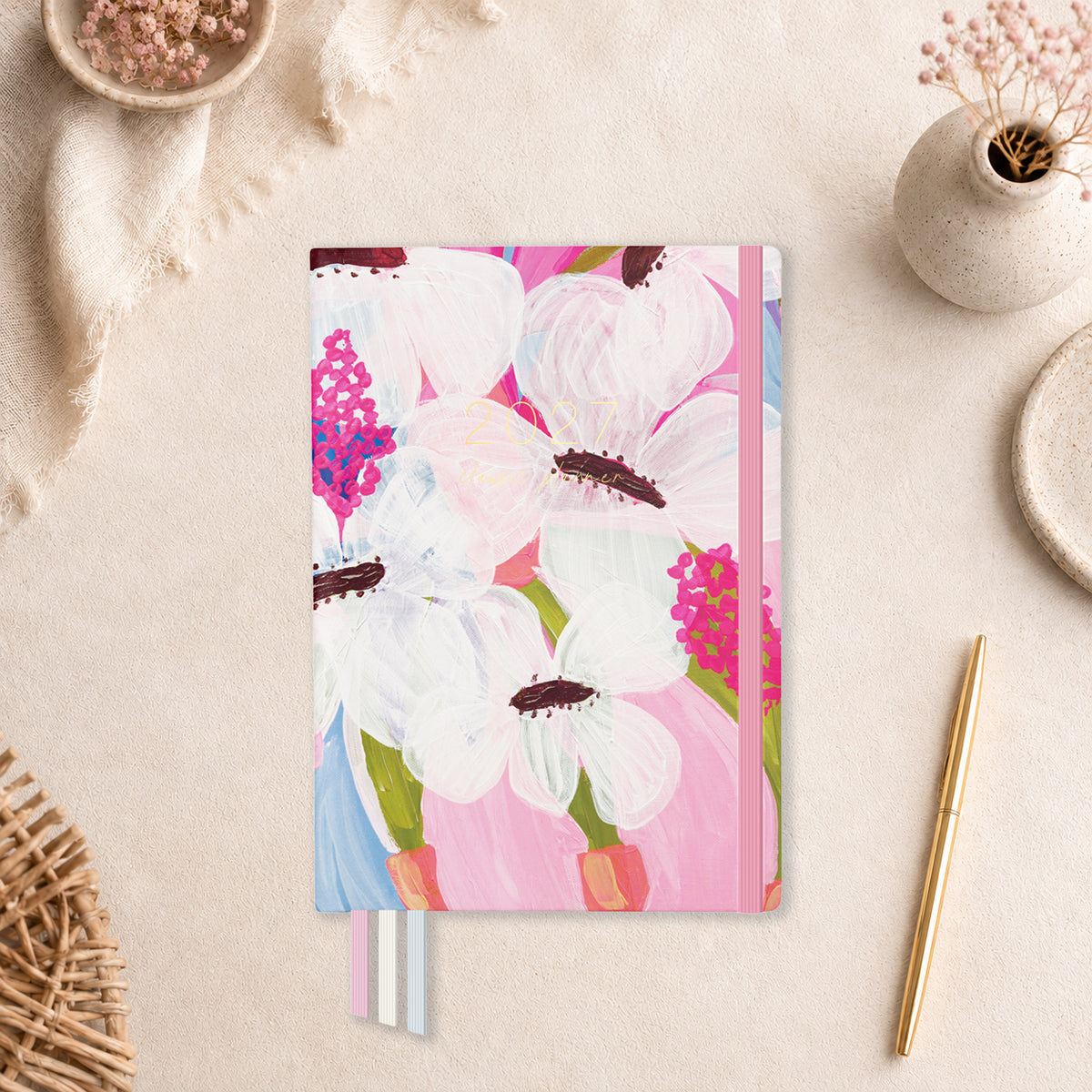 2027 Petals Classic Weekly Teacher Planner flat lay with painted white flowers on pink, styled with dried florals on a neutral desk