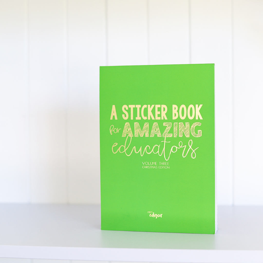 Green A5 sticker book standing upright on a desk, with gold-foiled text 'A Sticker Book for Amazing Educators Volume 3 Christmas Edition' and 'Mrs Edgar' at the bottom, with a gold elastic enclosure.
