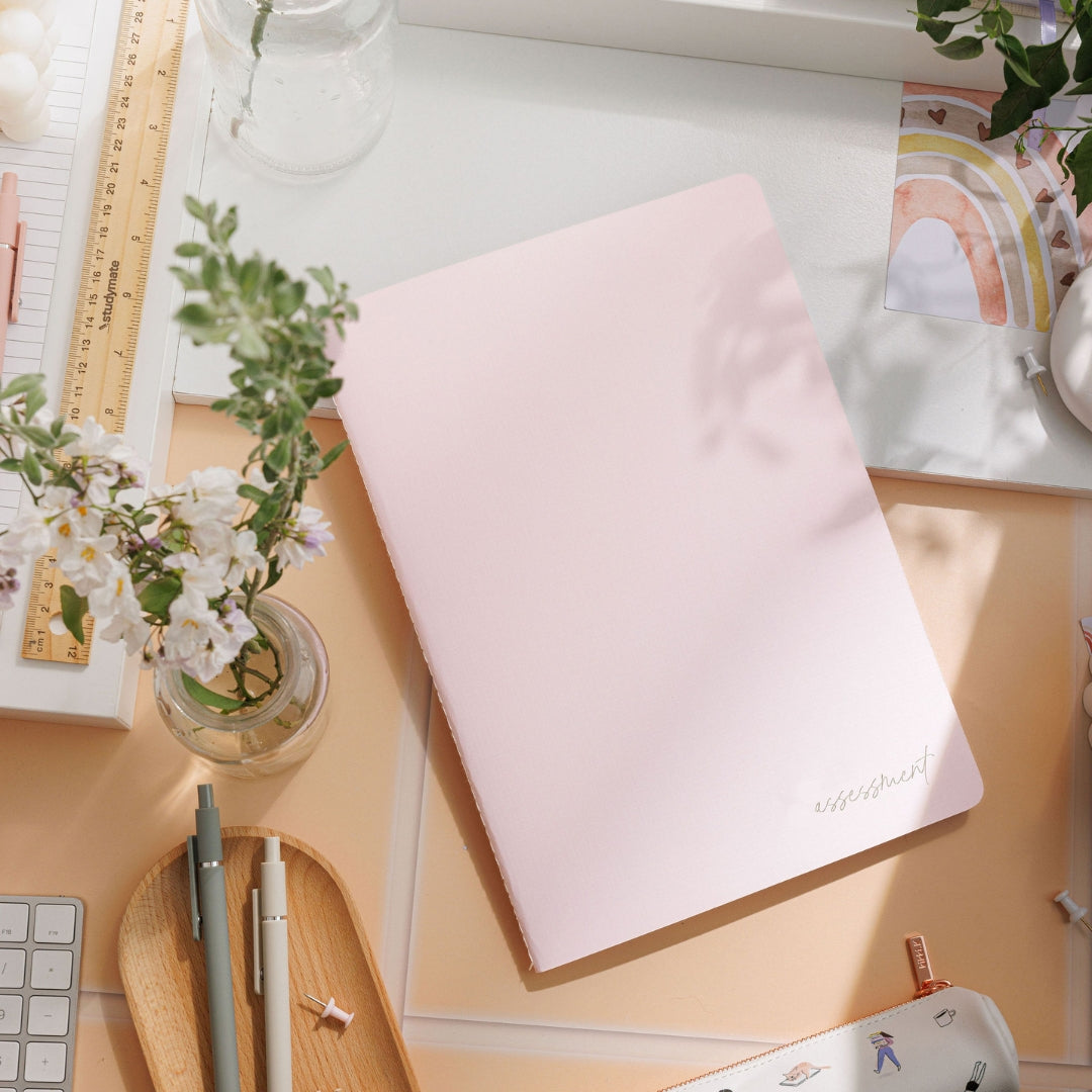 Blush assessment journal resting flat on a decorative surface, emphasising its sleek design. 