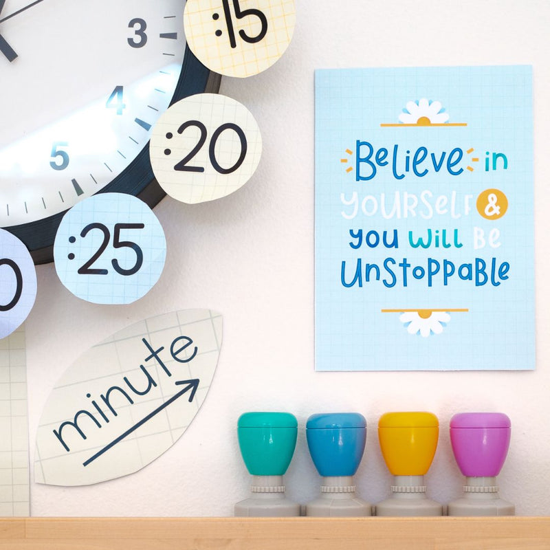 Gentle Classroom Decor Set with an inspirational poster, colourful stamps, and the bottom right corner of a clock visible.