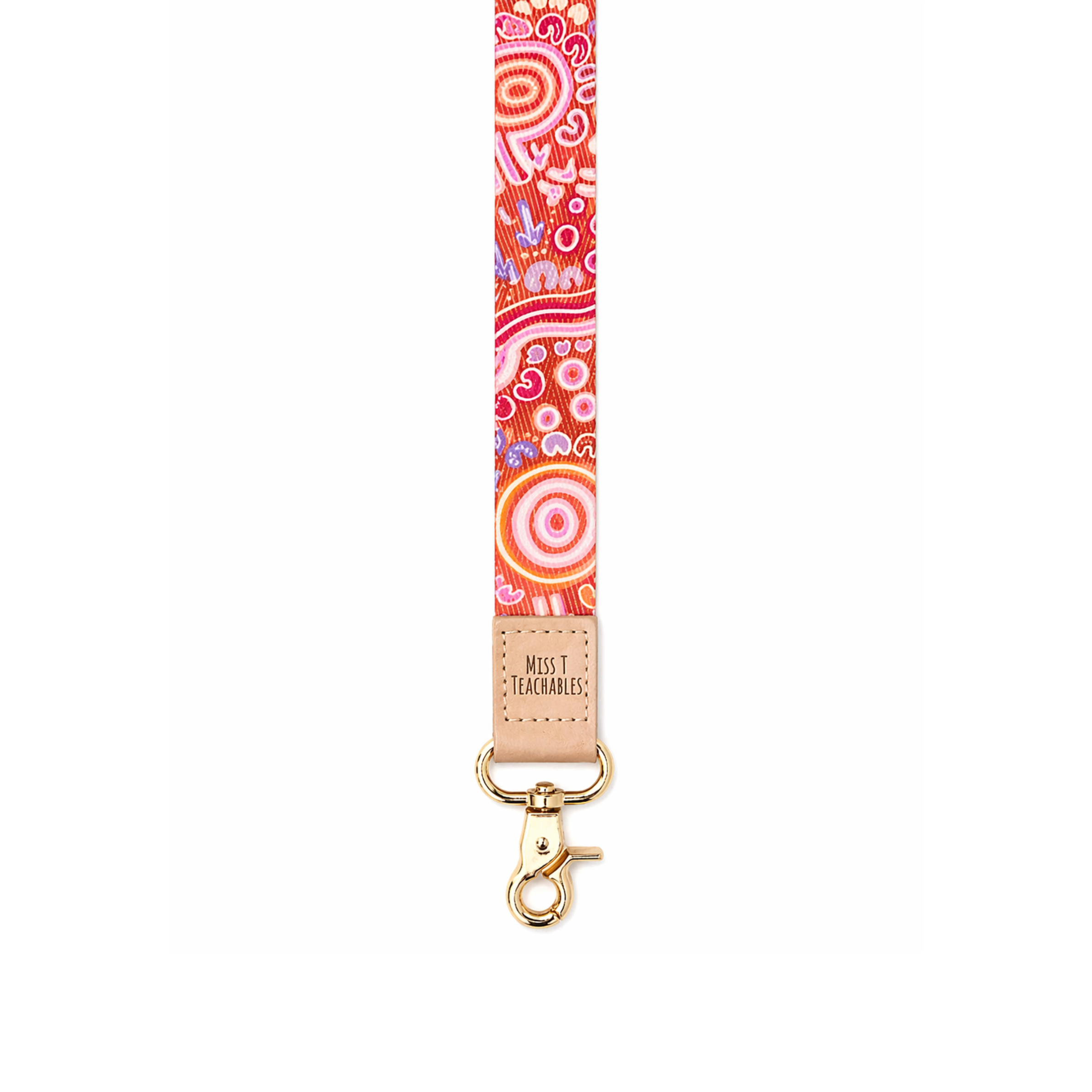 Red and pink Indigenous-inspired patterned fabric lanyard with tan leather “Miss T Teachable” logo patch and gold clasp on a clean white background.