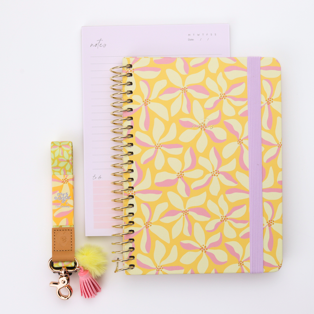 Yellow floral A5 teacher notebook with lilac elastic band paired with coordinating floral lanyard and lined notepad flat lay