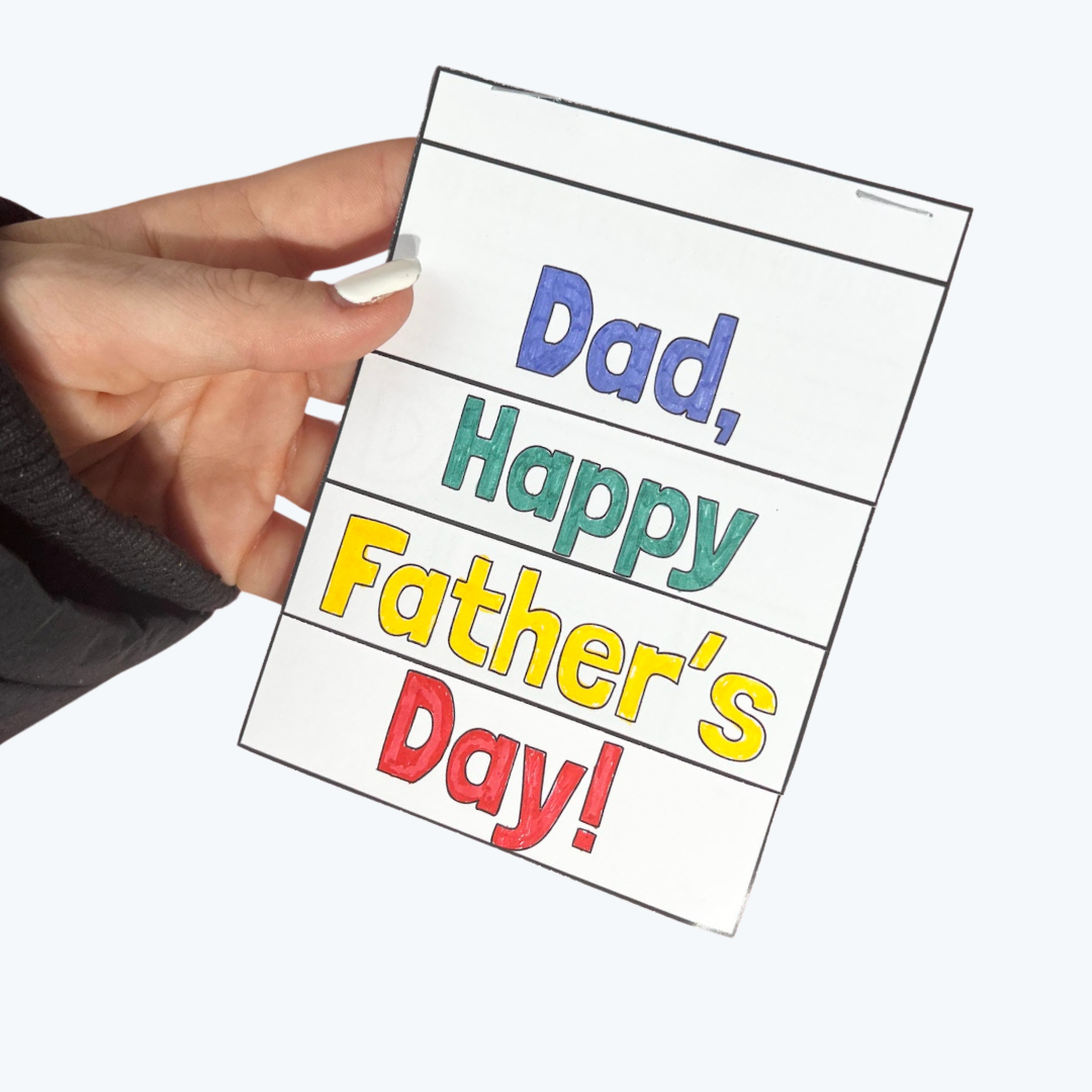 A person holds a handmade Father's Day flipbook with "Dad, Happy Father’s Day!" written in colourful, bold letters. The booklet is stapled at the top, and the person’s nails are painted white.