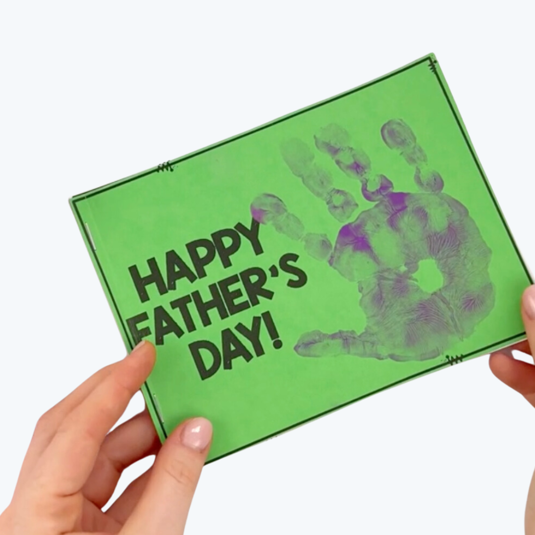 A handmade Father's Day card with a green background, bold black text reading 'Happy Father's Day!' and a purple handprint design.