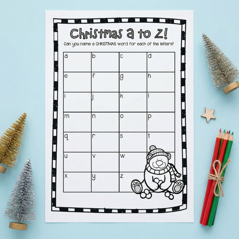 Black-and-white “Christmas A to Z!” printable worksheet asking students to write a Christmas-related word for each letter of the alphabet. The page features a grid labeled with lowercase letters a–z and a cartoon teddy bear in winter clothing at the bottom. The worksheet is displayed on a light blue background with small Christmas trees, a wooden star, and colored pencils.