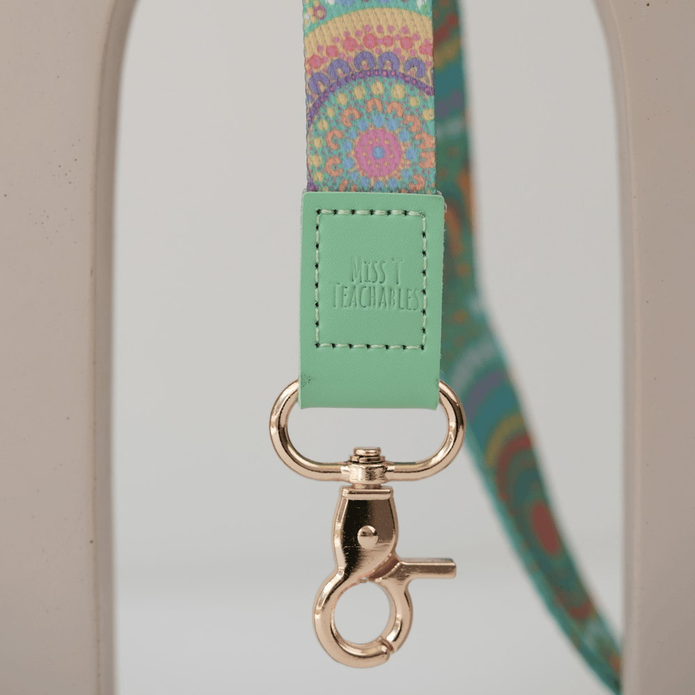 Close up of A Calming Force teacher lanyard clasp, embossed Miss T Teachables mint tab and gold swivel clasp