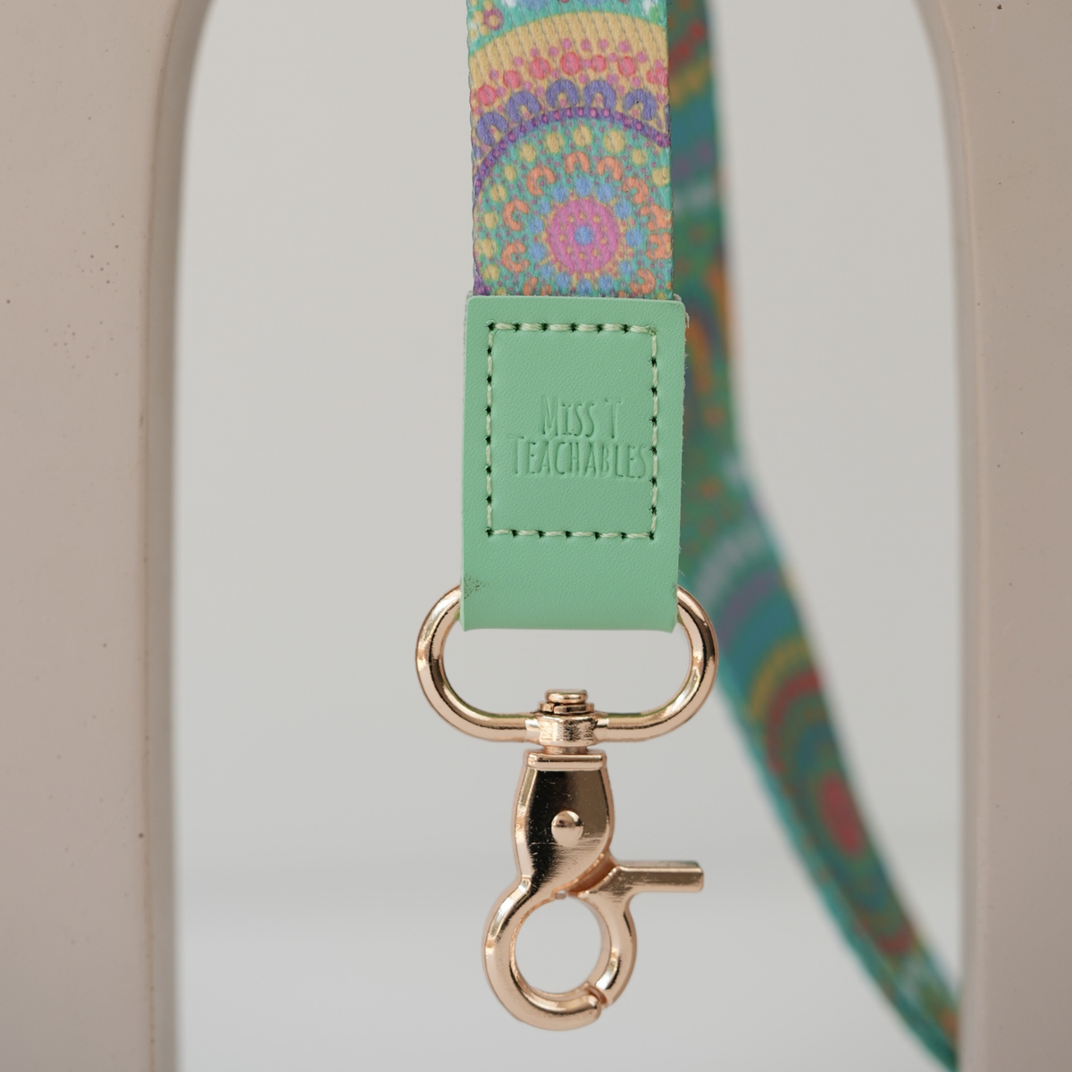 Close up of A Calming Force teacher lanyard clasp, embossed Miss T Teachables mint tab and gold swivel clasp