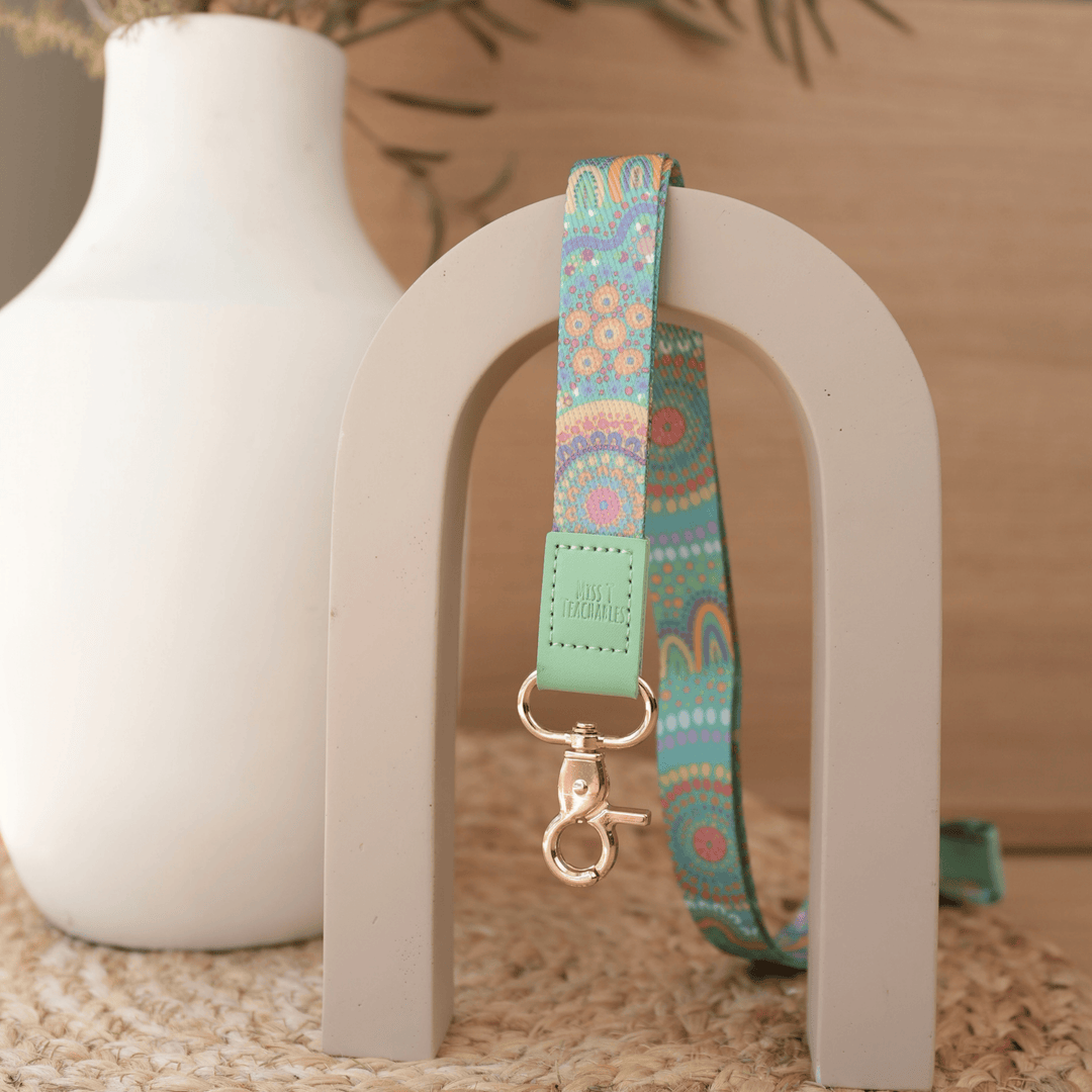 A Calming Force teacher lanyard by Muthi Tidda, turquoise dot artwork with mint leather tab and gold clasp