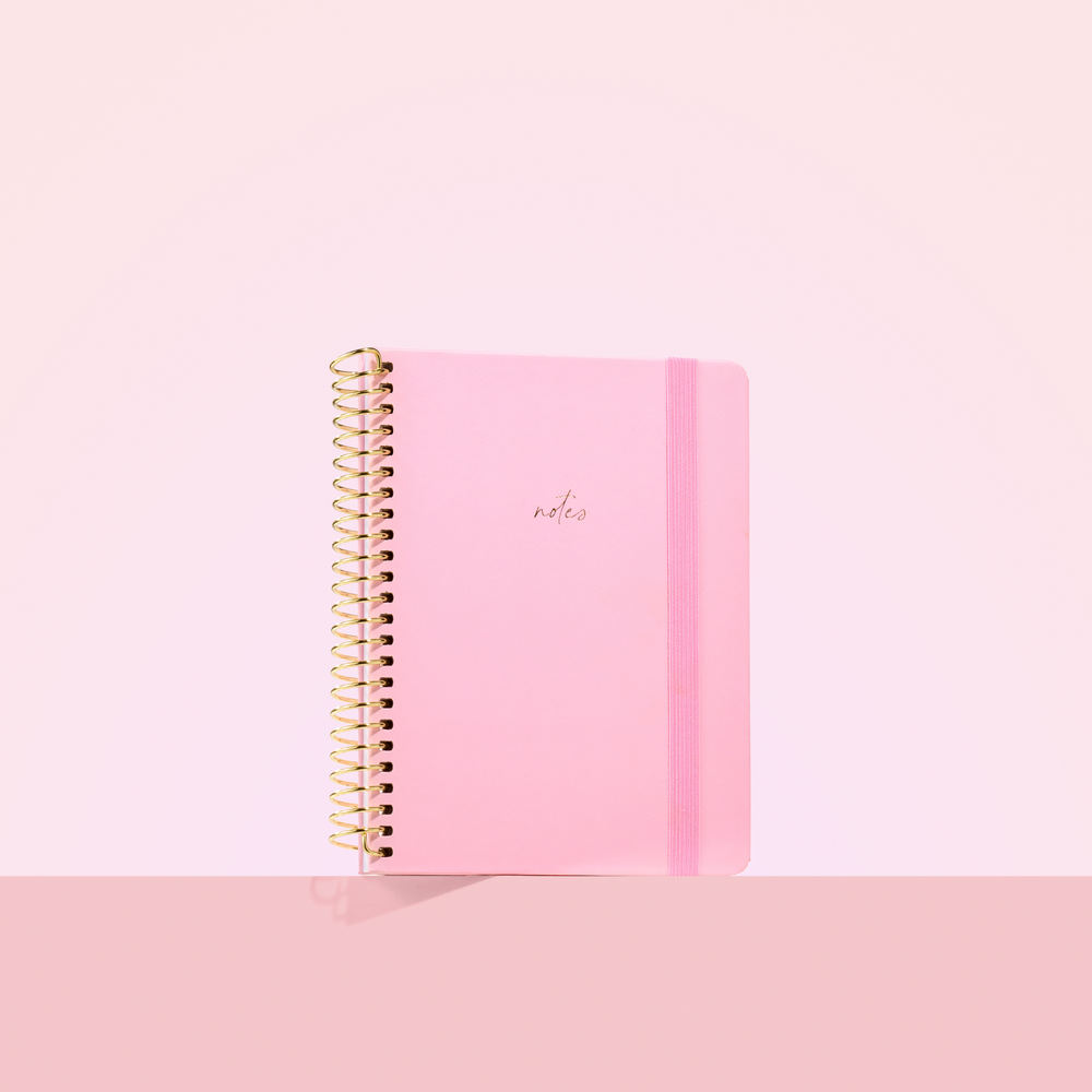 Blush pink 2026 notepad with gold spiral binding, elastic closure, and the word "notes" embossed in gold on the cover.