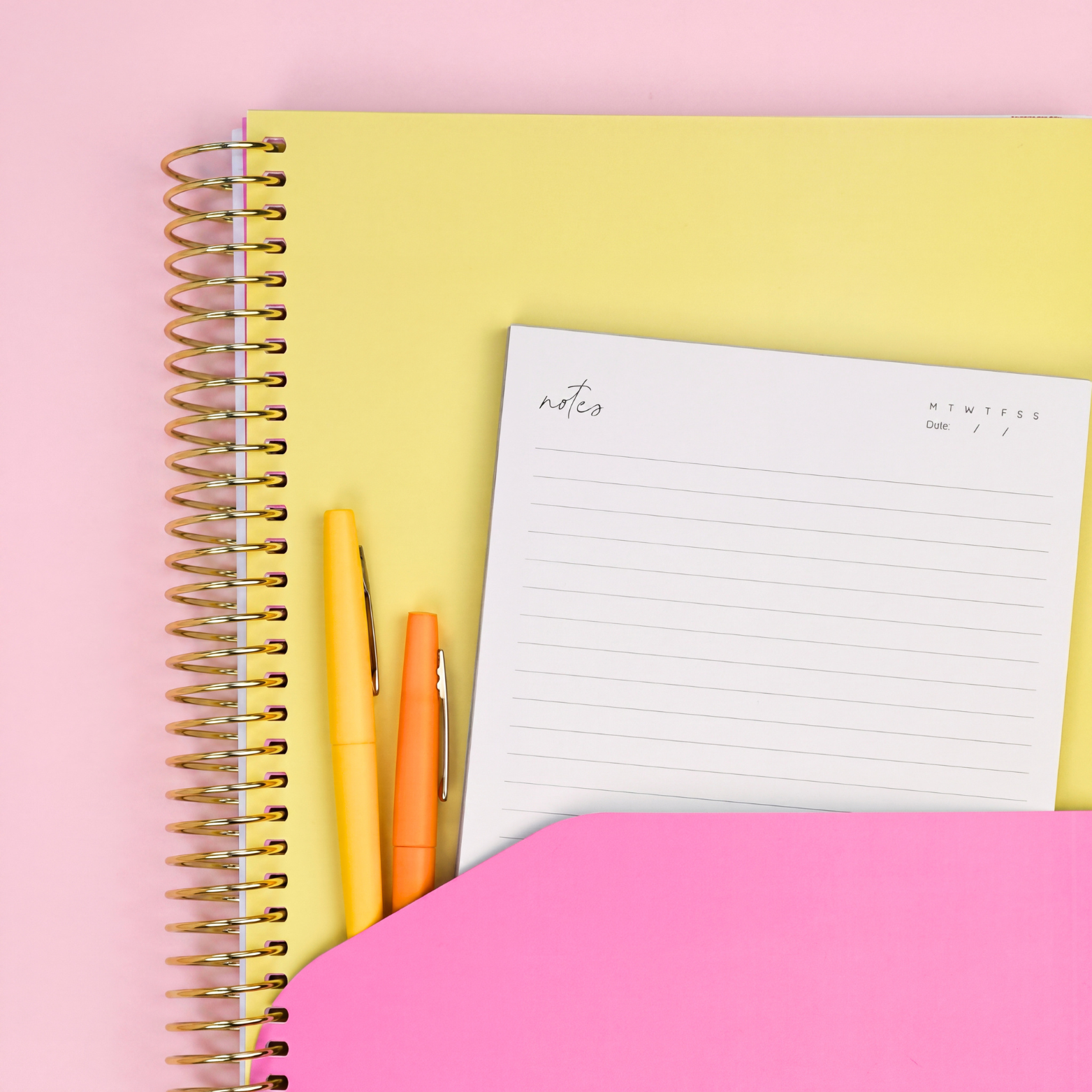 2027 Butter Daily Planner showing pink pocket sleeve with notes page and yellow pens, gold coil on a pink background.