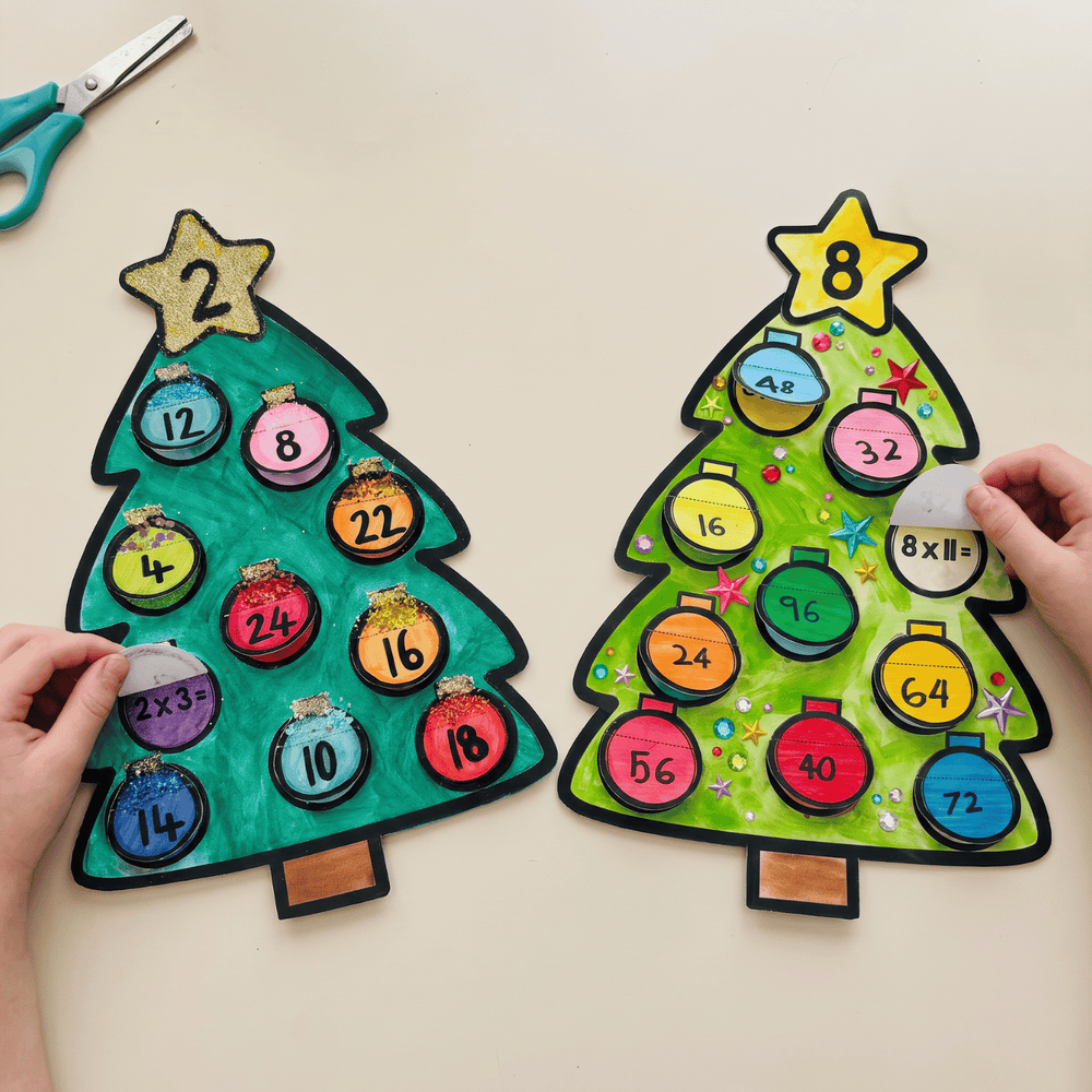 Hands lifting a bauble on each finished Christmas tree to reveal the multiplication fact hidden underneath, showing 2 x 3 on the teal two times table tree and 8 x 11 on the green eight times table tree.