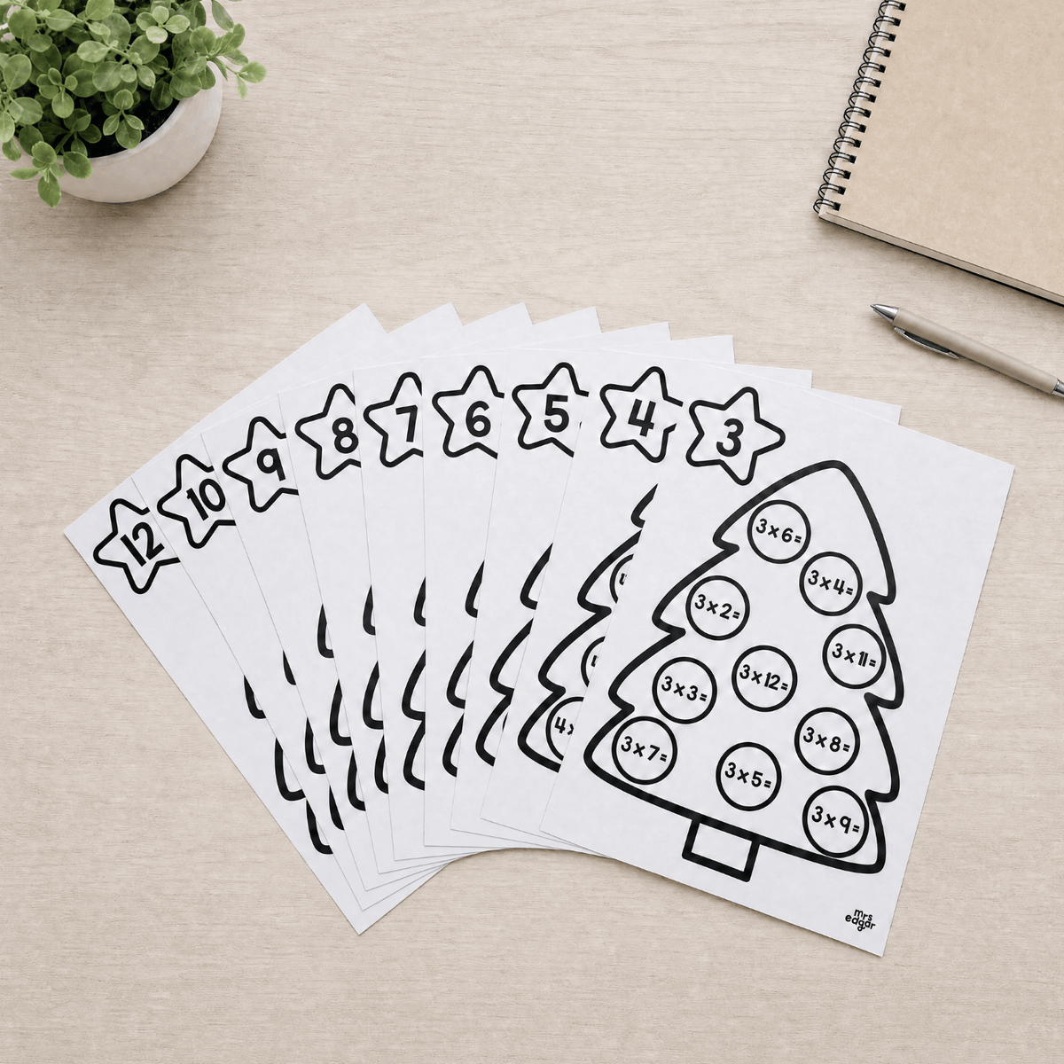 The eleven single table Christmas tree sheets fanned out in black and white, with the table number printed on each star from three through to twelve and ten multiplication facts in bauble circles.