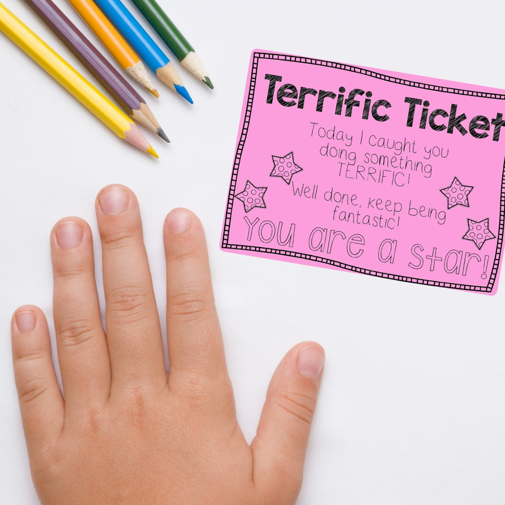 Teacher rewards student Hand holding a 'Terrific Ticket' with colorful pencils on a white background