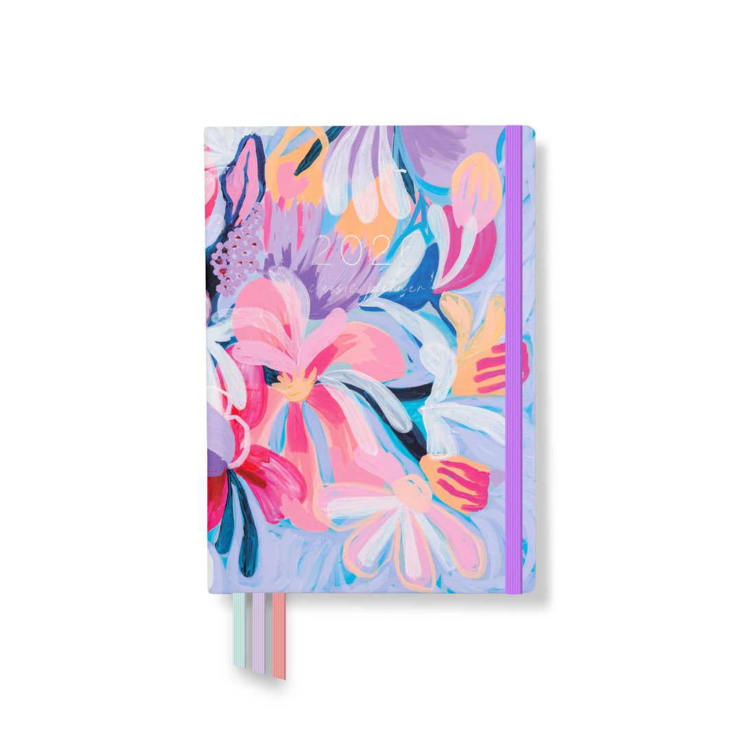 2026 classic planner front cover with bold hand-painted floral artwork in pinks, purples, and blues, with a purple elastic and pastel ribbons.