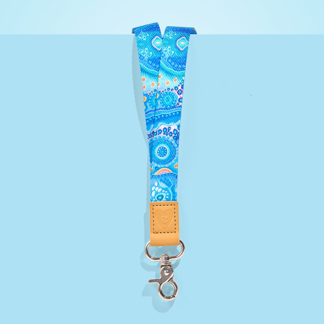 Blue Aboriginal art teacher lanyard with tan leather accent and silver clasp, displayed on a light blue background.