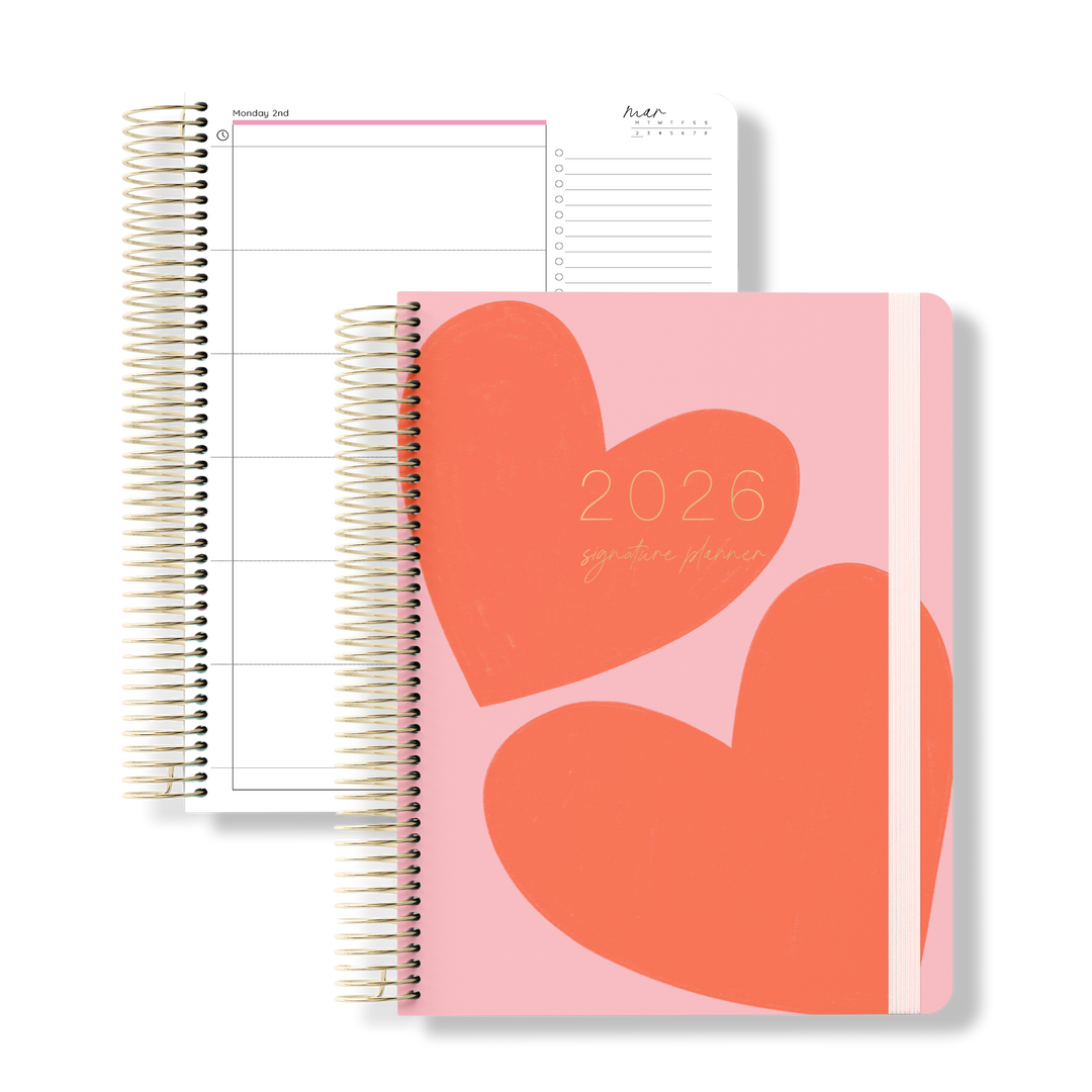 2026 daily teacher planner with bold red heart illustrations on a pink cover, shown next to a structured daily planning spread.