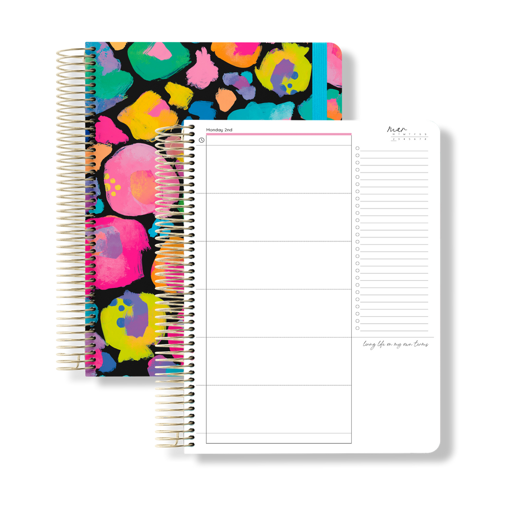 2026 signature planner with a bold rainbow leopard print cover and blue elastic, shown next to an open daily planning page.