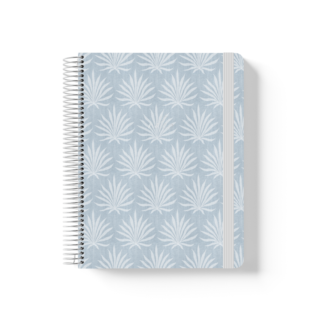 Palms spiral notebook with a repeating white palm frond pattern on a soft blue-grey background, silver coil binding, and grey elastic closure.