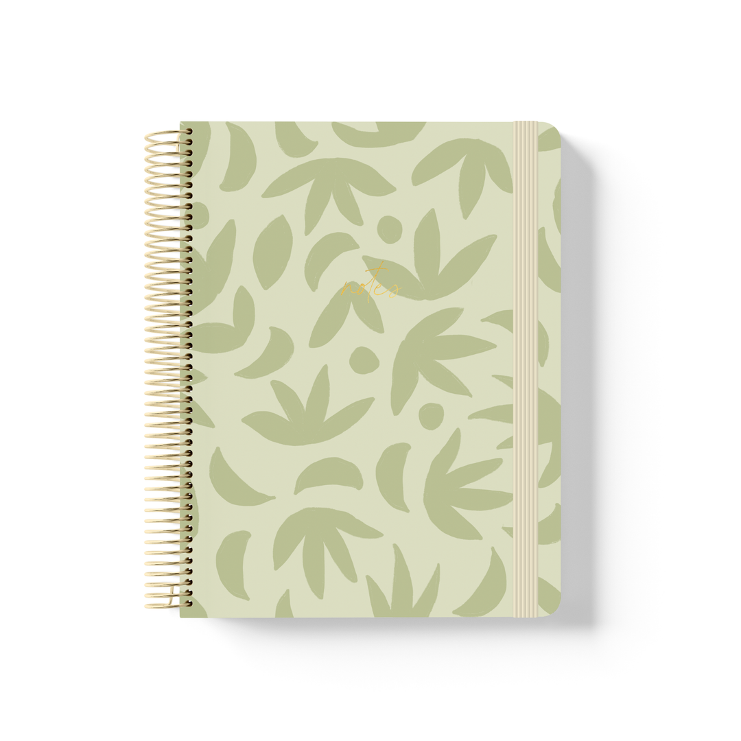 Sunburst Sage spiral notebook with a sage green botanical leaf pattern on a pale green background, gold coil binding, and cream elastic closure.