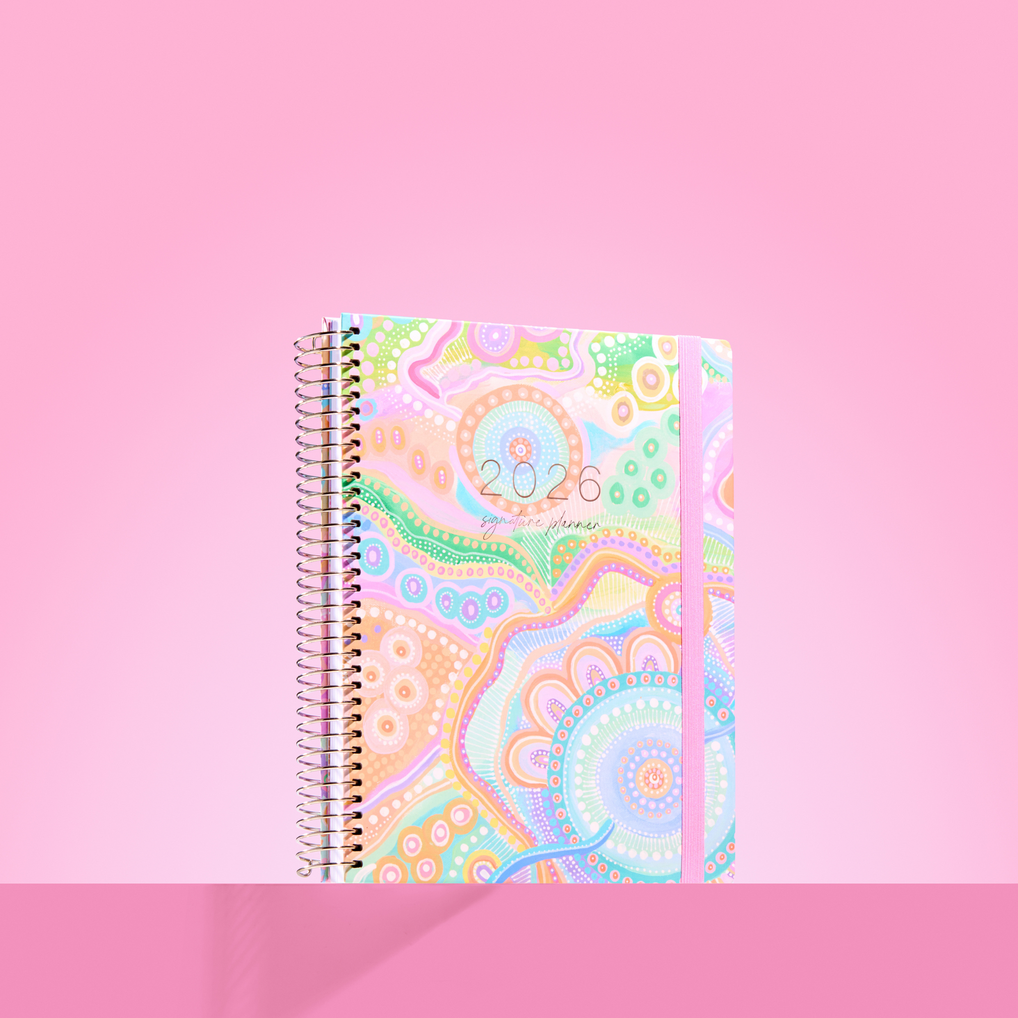 2026 teacher planner with pastel Aboriginal-style artwork, silver coil binding, and lavender elastic strap.
