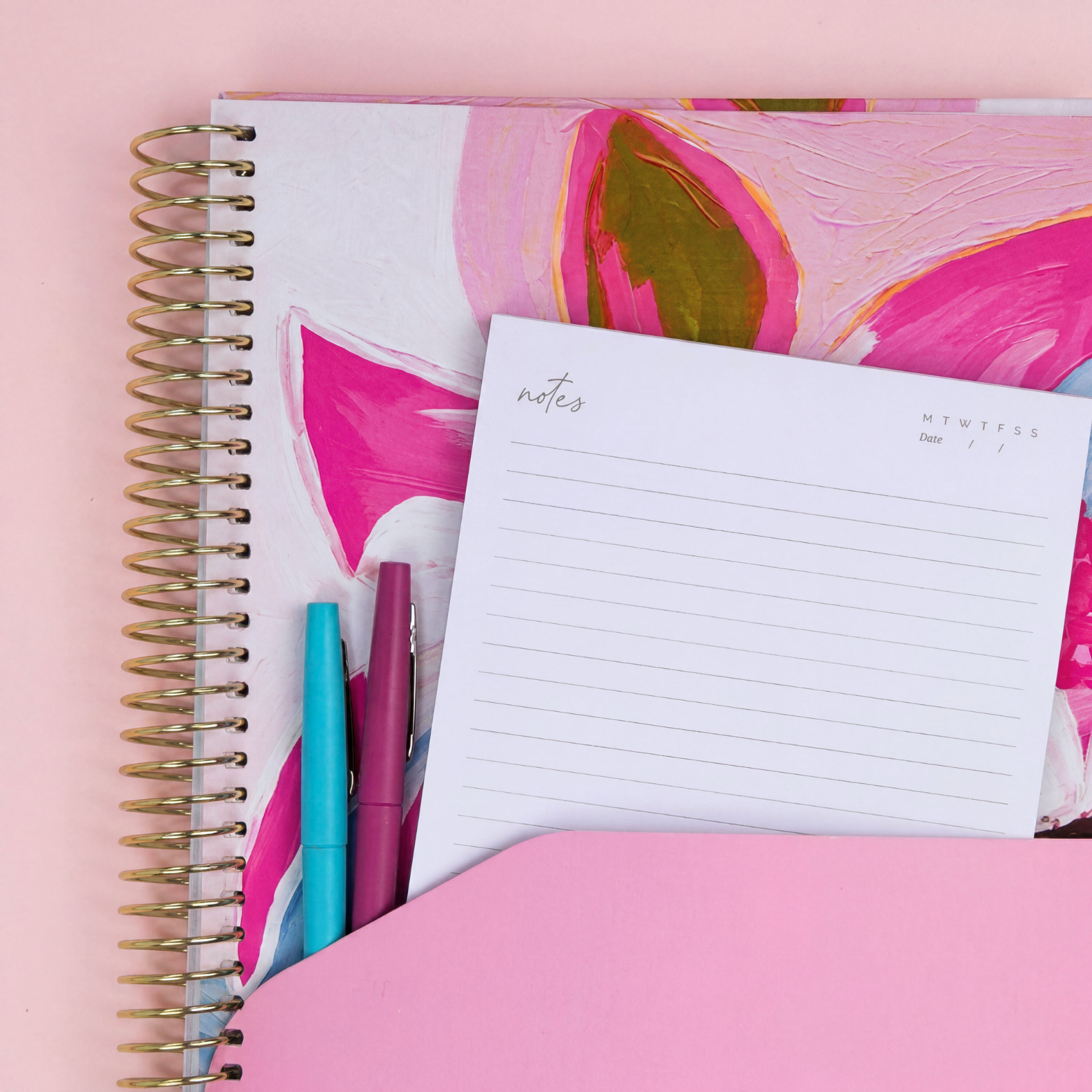 2027 Petals Signature Planner showing pink pocket sleeve with notes page and coloured pens, gold coil on a pink background.
