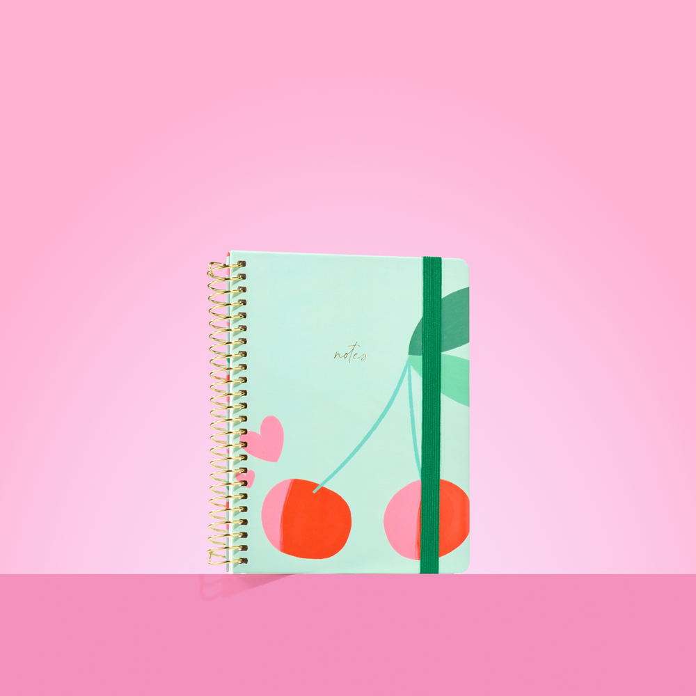 Mint green 2026 notepad with red cherries, green leaves, pink heart, gold spiral binding, and dark green elastic closure.