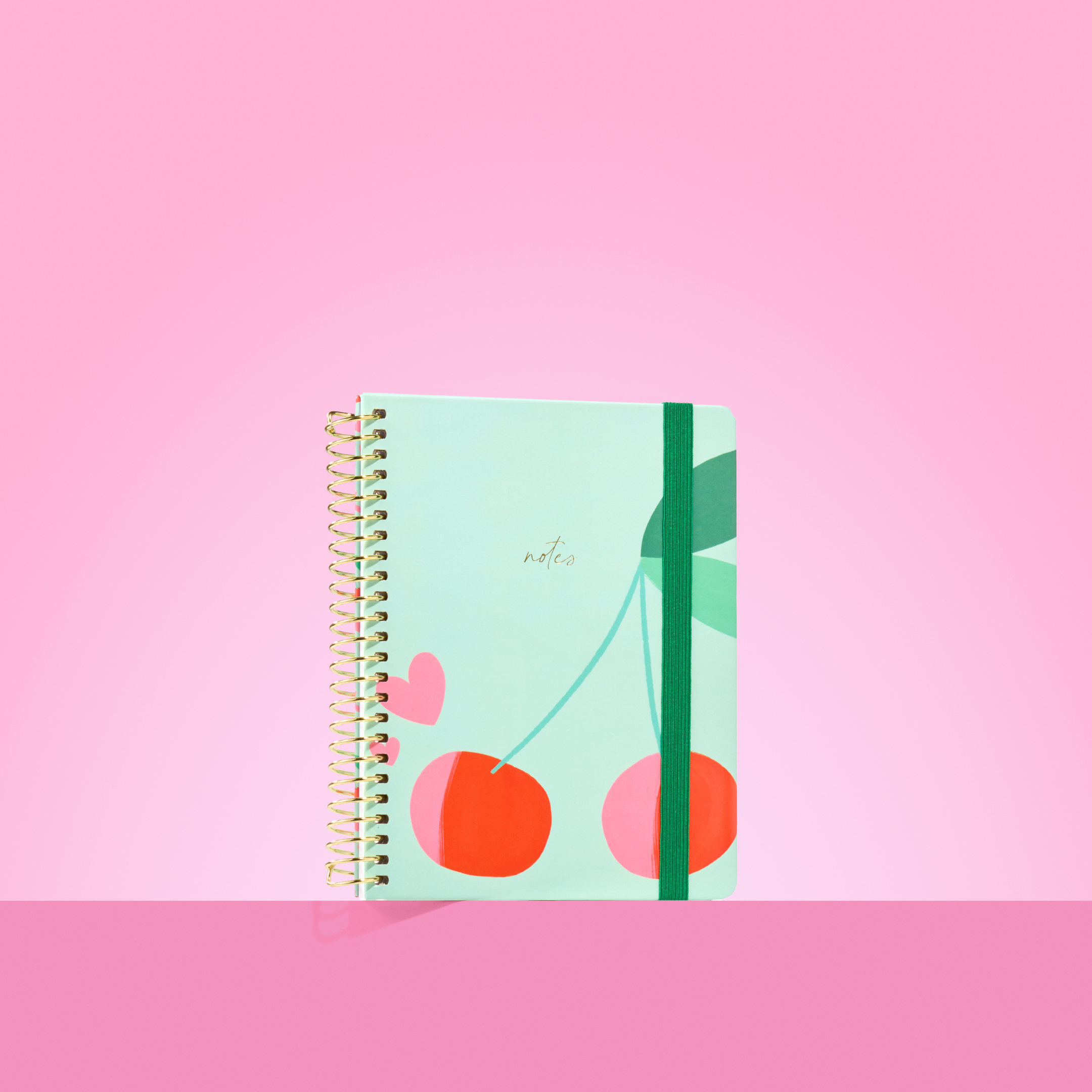 Mint green 2026 notepad with red cherries, green leaves, pink heart, gold spiral binding, and dark green elastic closure.