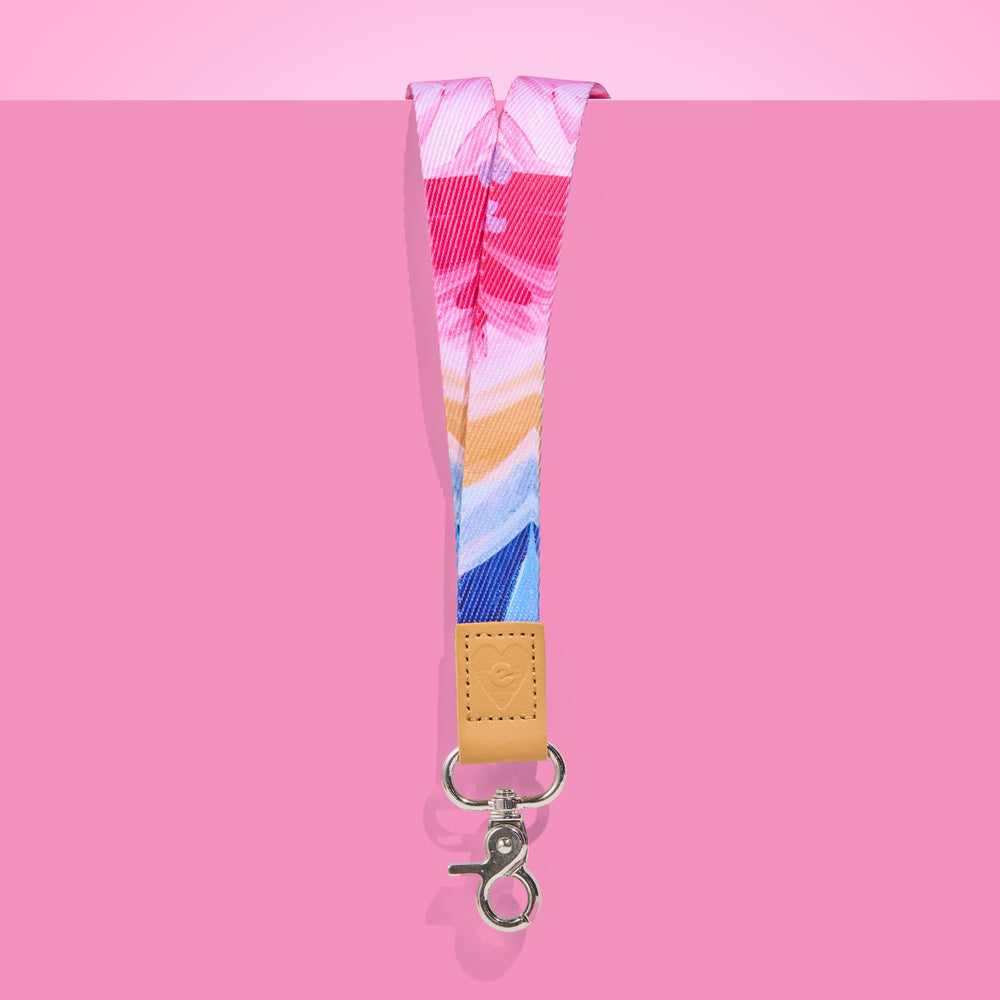 Colourful abstract teacher lanyard with shades of pink, blue and gold, featuring tan leather accent and silver clasp on a pink background.