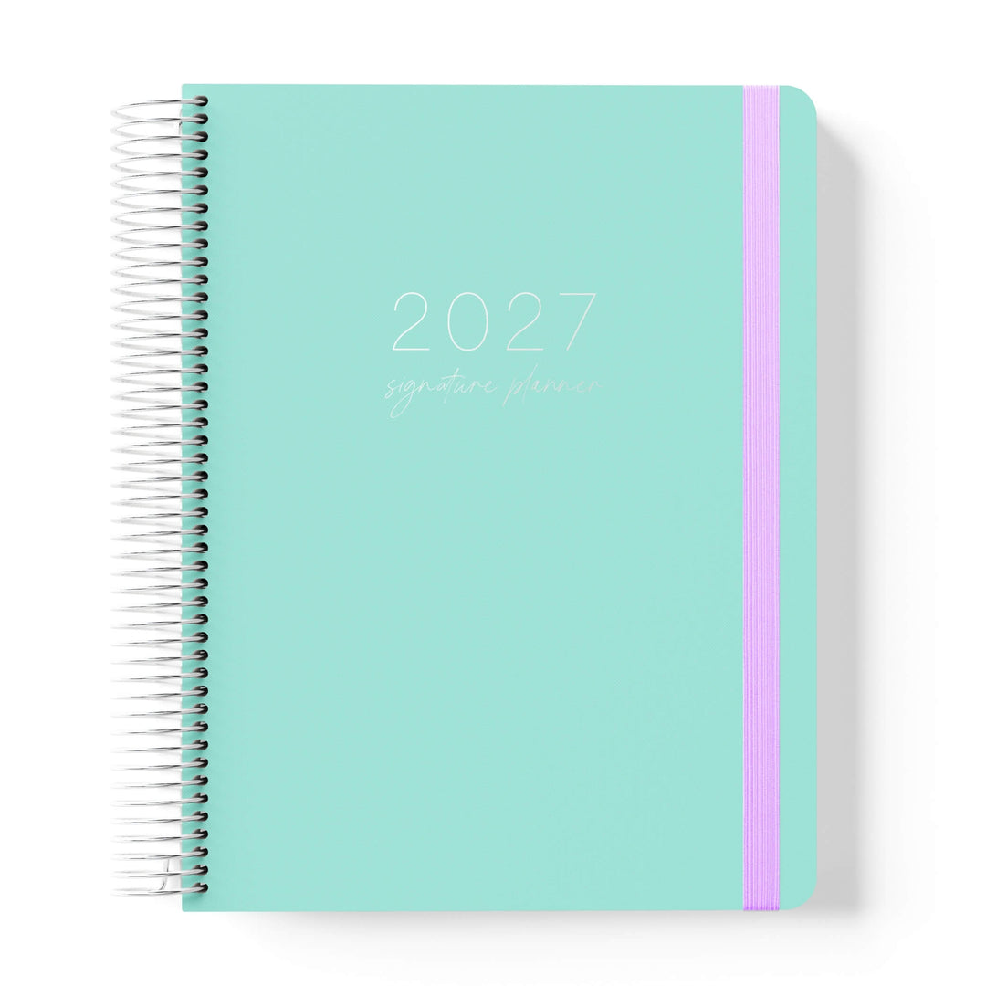 2027 Signature Planner in Seafoam with tonal text on a mint green cover, silver coil binding, and lilac elastic closure.