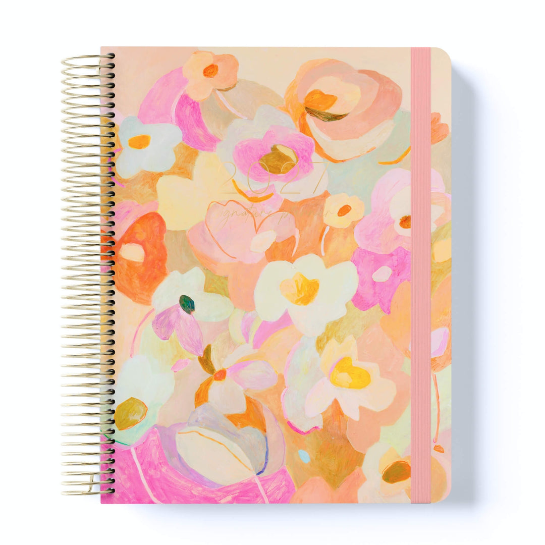 2027 Signature Planner in Love Fool with painted floral artwork in pink, peach and cream, gold coil binding, and pink elastic closure.