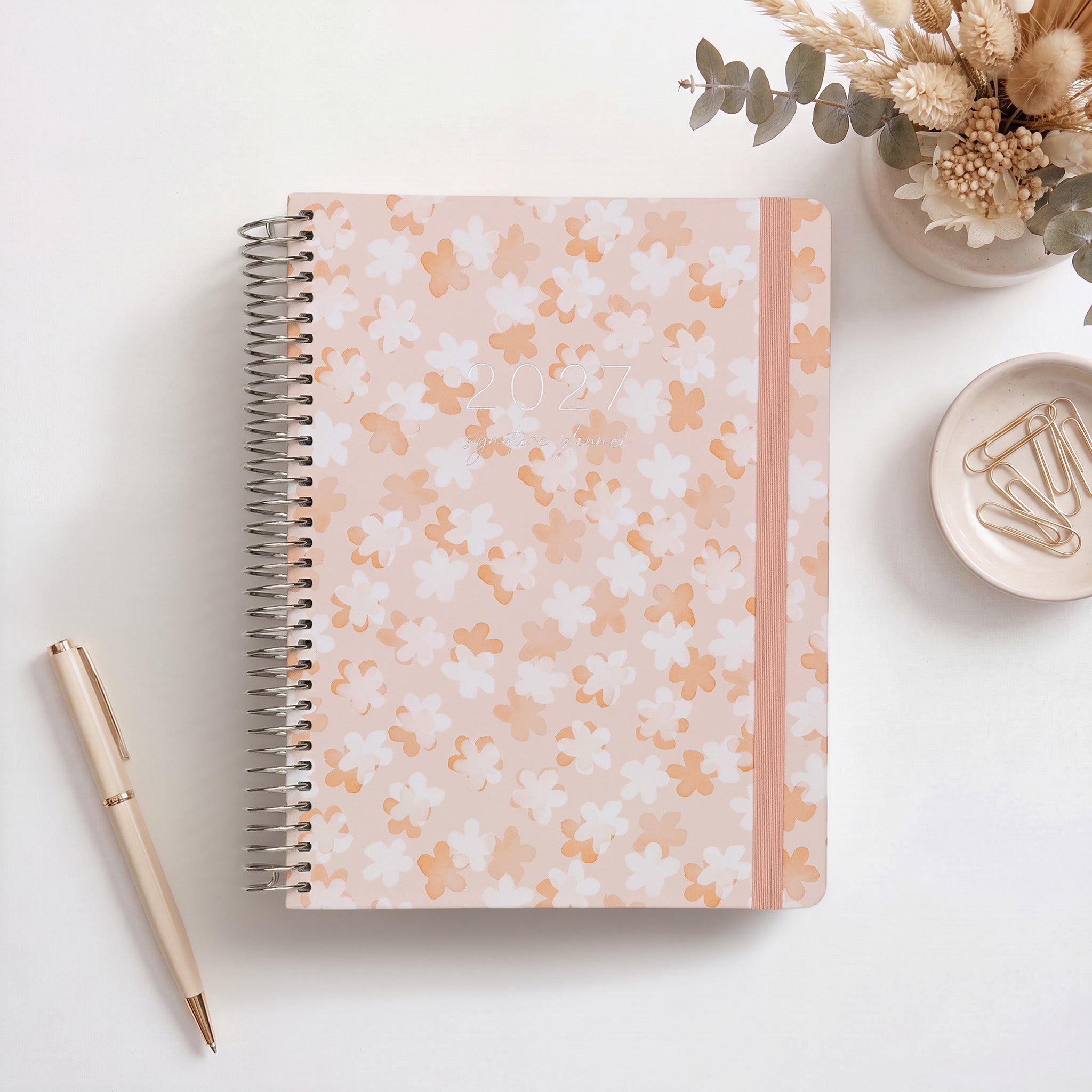 2027 Signature Planner in So Sweet with daisy pattern, styled with dried florals, silver coil and pink elastic closure.