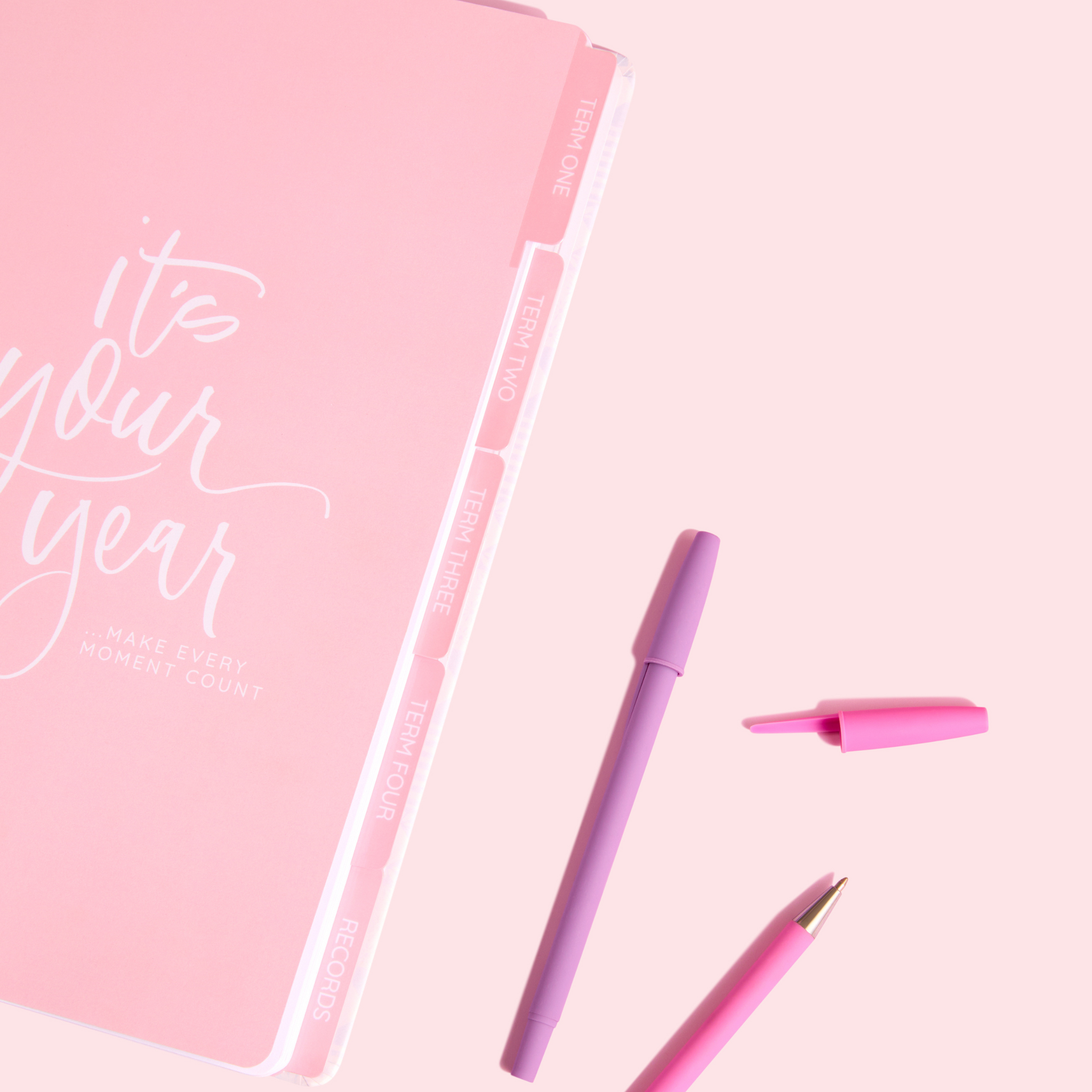 Pink divider page with “It’s your year” message and labeled tabs for each term, surrounded by pink and purple pens.