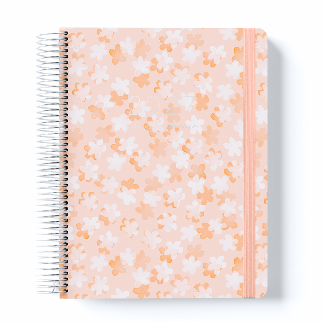 Peach floral 2027 signature planner with white and orange flower pattern, silver spiral binding, and elastic closure band.