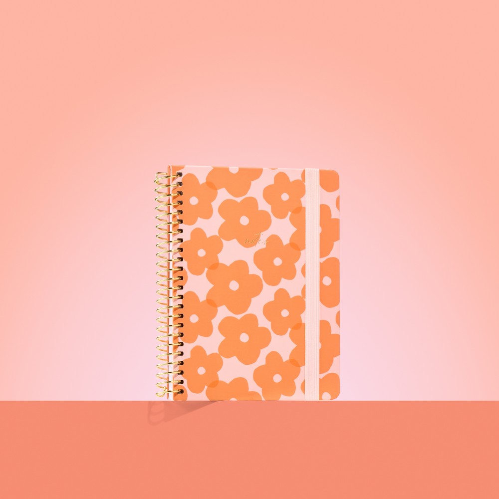 Peach-toned 2026 notepad with bold orange flower pattern, gold spiral binding, pale pink elastic closure, and gold "notes" text.
