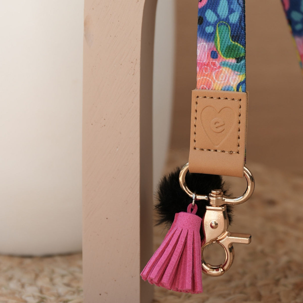 Close up of Boom teacher lanyard, bright Kasey Rainbow print, gold clasp, black pom pom and hot pink tassel