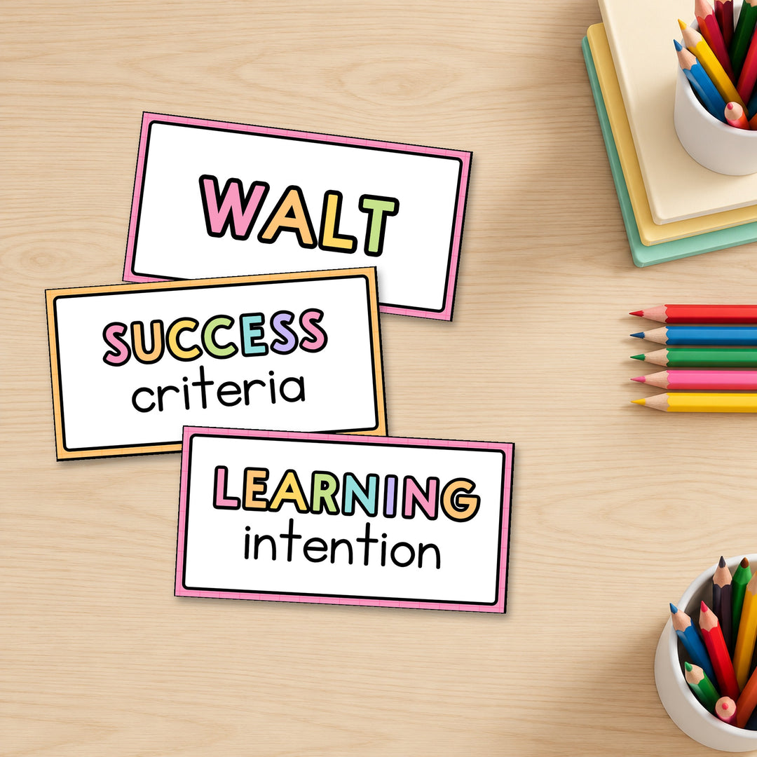 Three Learning Intention signs with rainbow caps standing on a desk, Bright colours