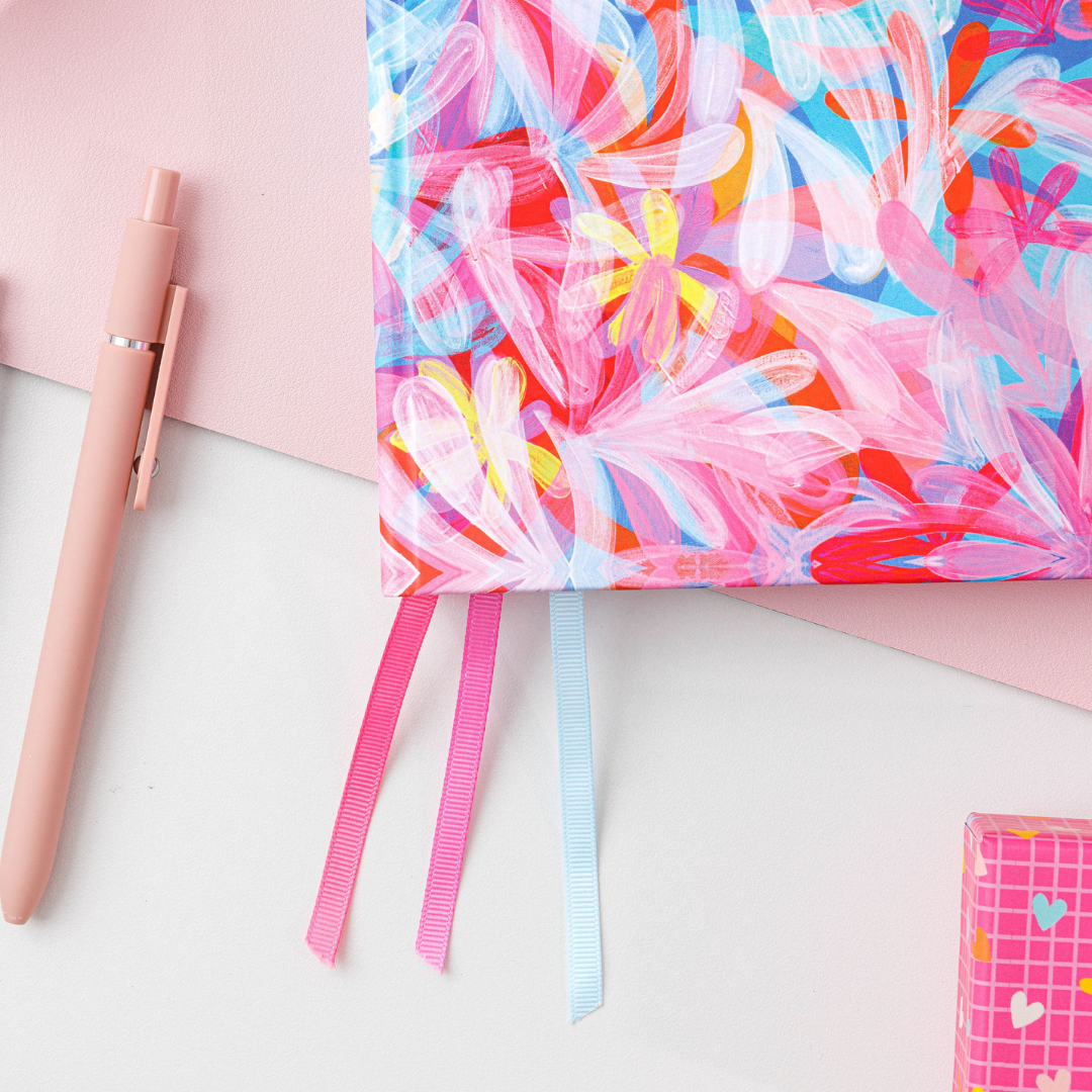 Close-up of the bottom left-hand corner of the general planner, showing ribbon dividers hanging out, as it rests on a desk.