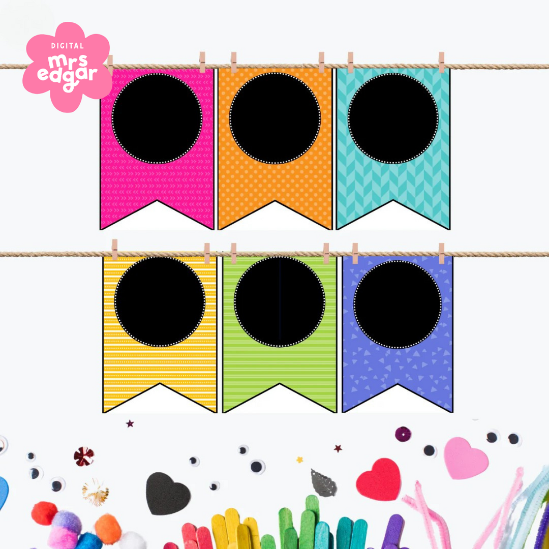 Six classroom bunting flags hung on a string with mini pegs. Flags include pink, orange, teal, yellow, green, and blue designs, all with different patterns and a central black circle. Decorative classroom background includes felt hearts, pom-poms, and googly eyes.